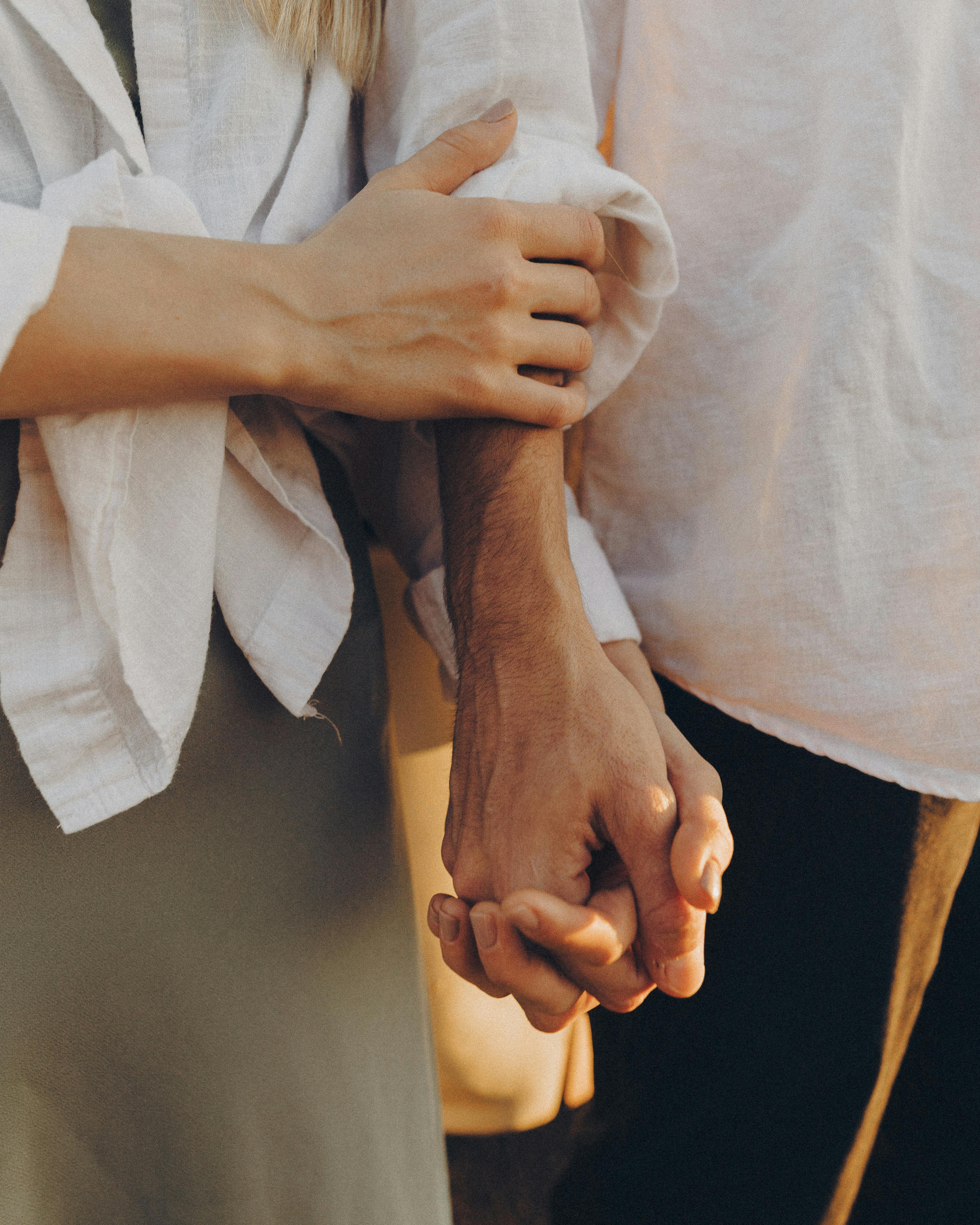 Eine Frau streichelt den Arm eines Mannes, während sie die Hände hält | Quelle: Pexels
