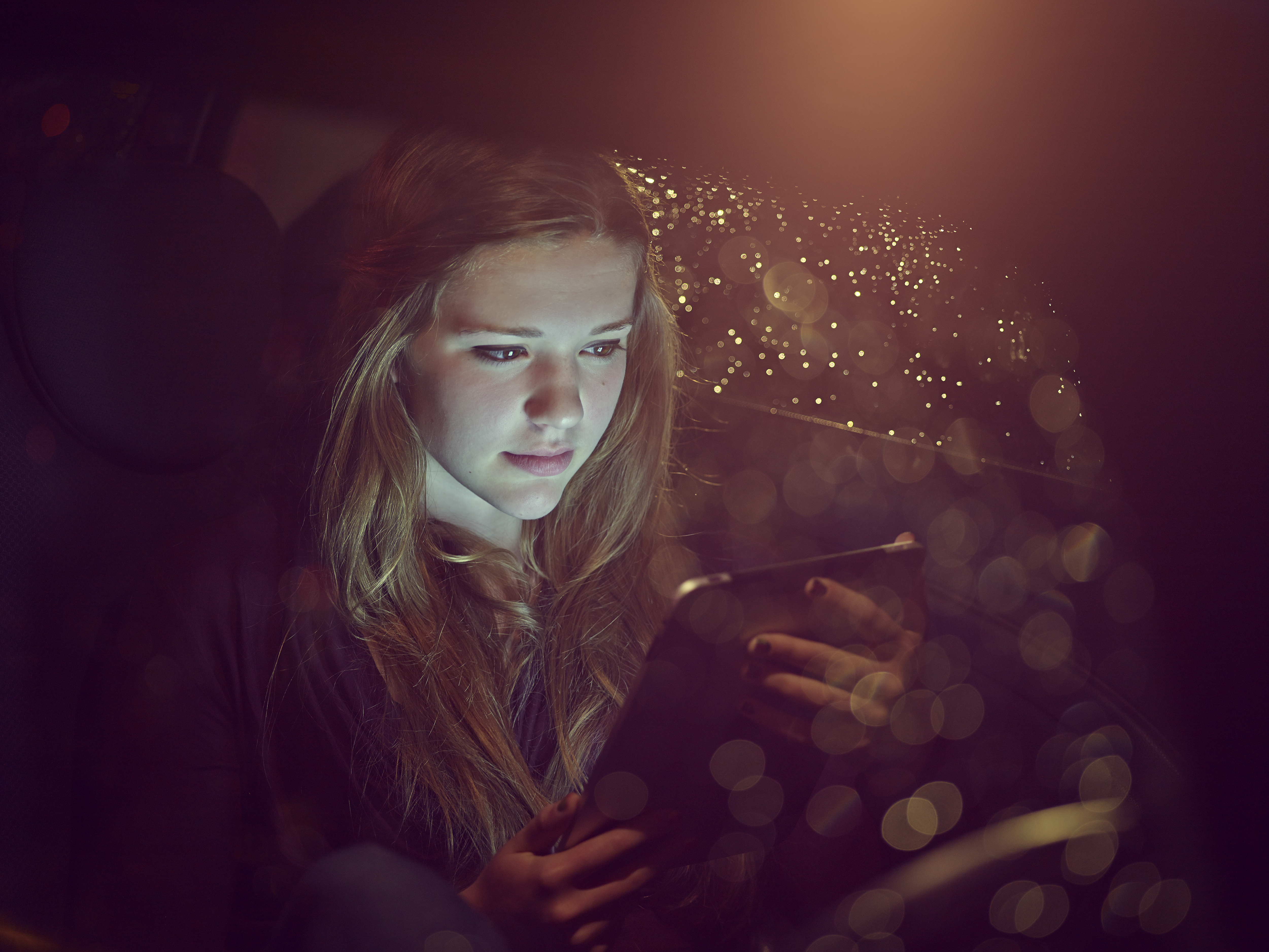 Mädchen an einem Tablet-Computer in einem Auto bei Nacht | Quelle: Getty Images