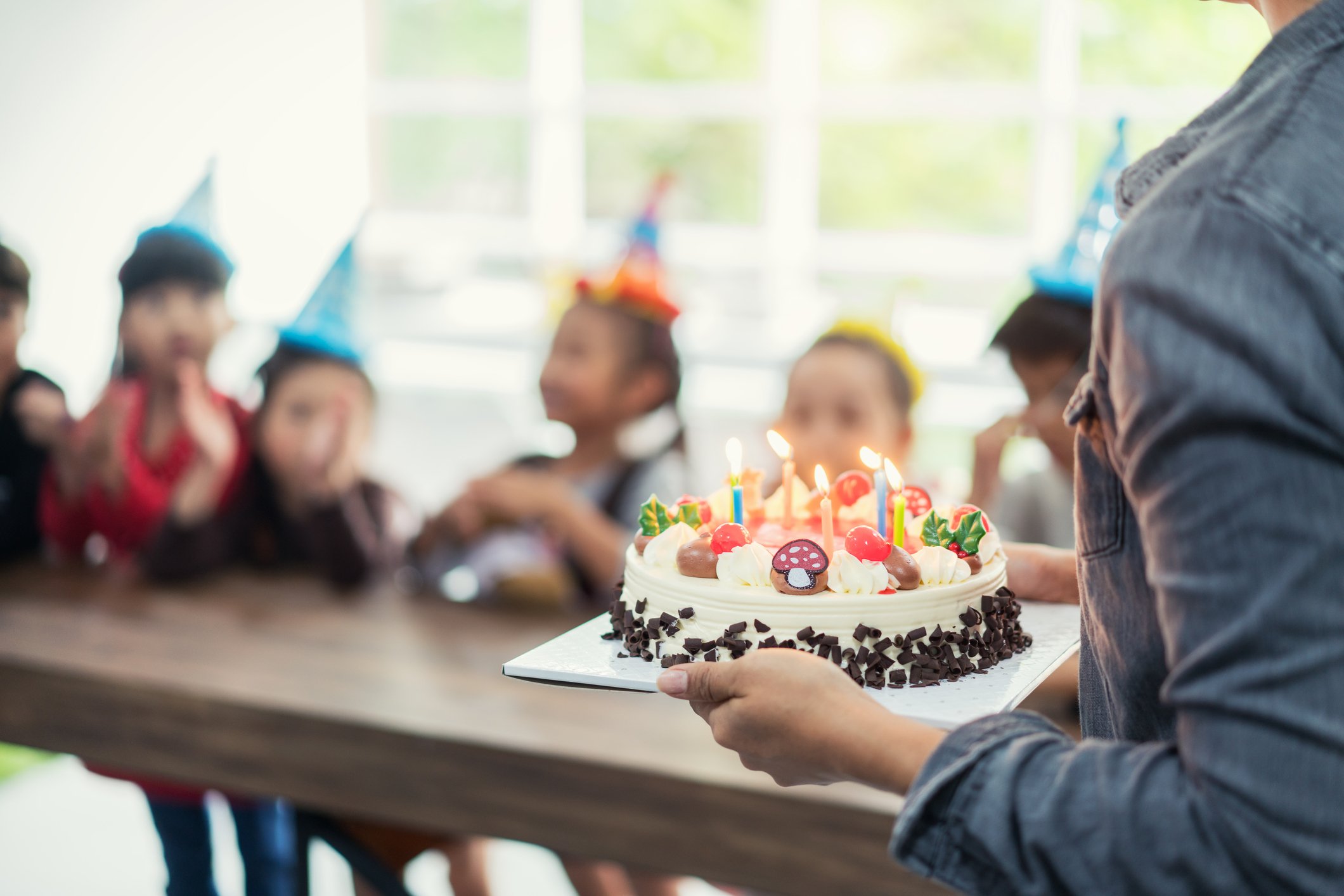 Gruppe entzückender Kinder, die Geburtstagstorte mit Kerze sehen | Quelle: Getty Images