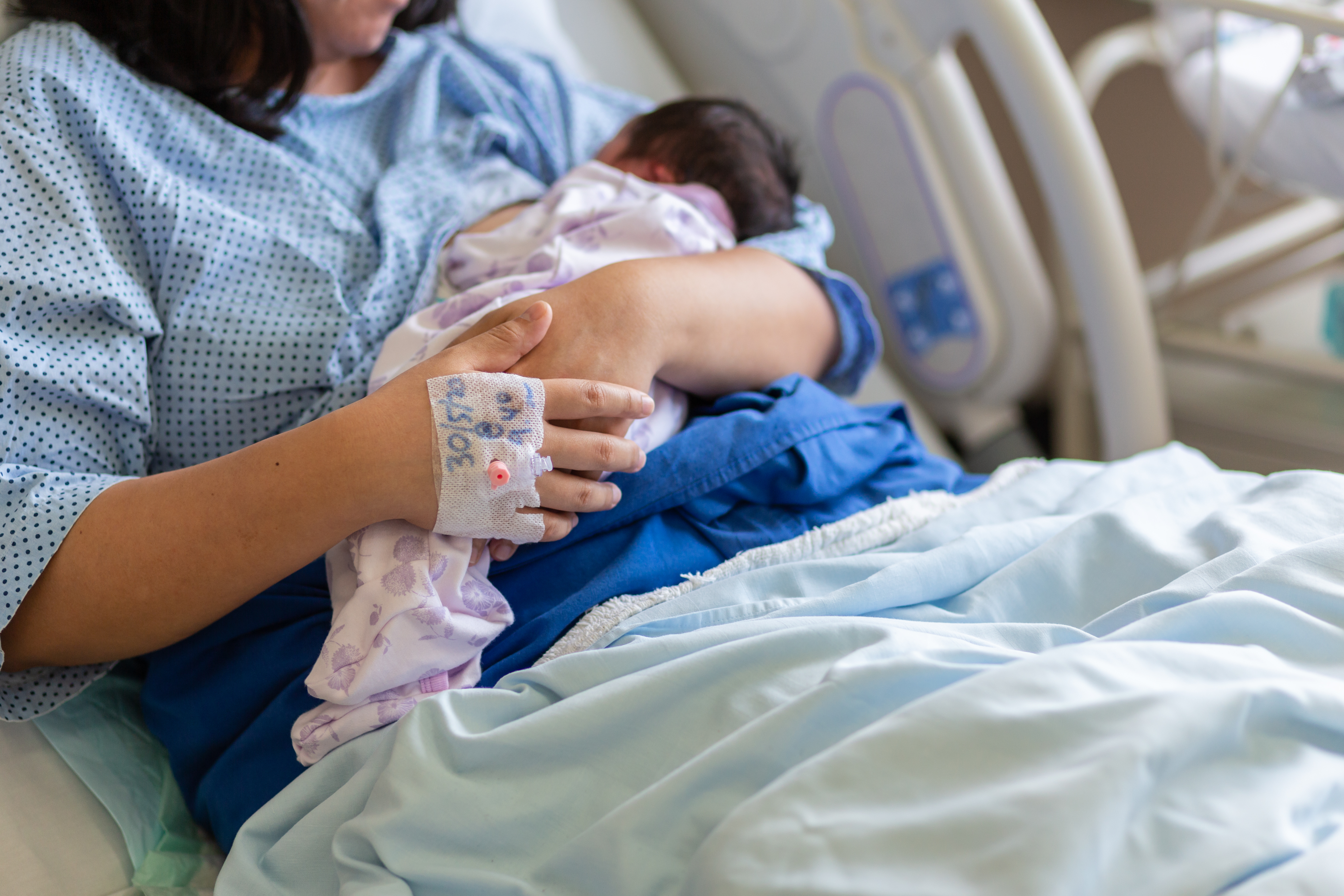 Eine Frau, die ein neugeborenes Baby im Arm hält | Quelle: Shutterstock