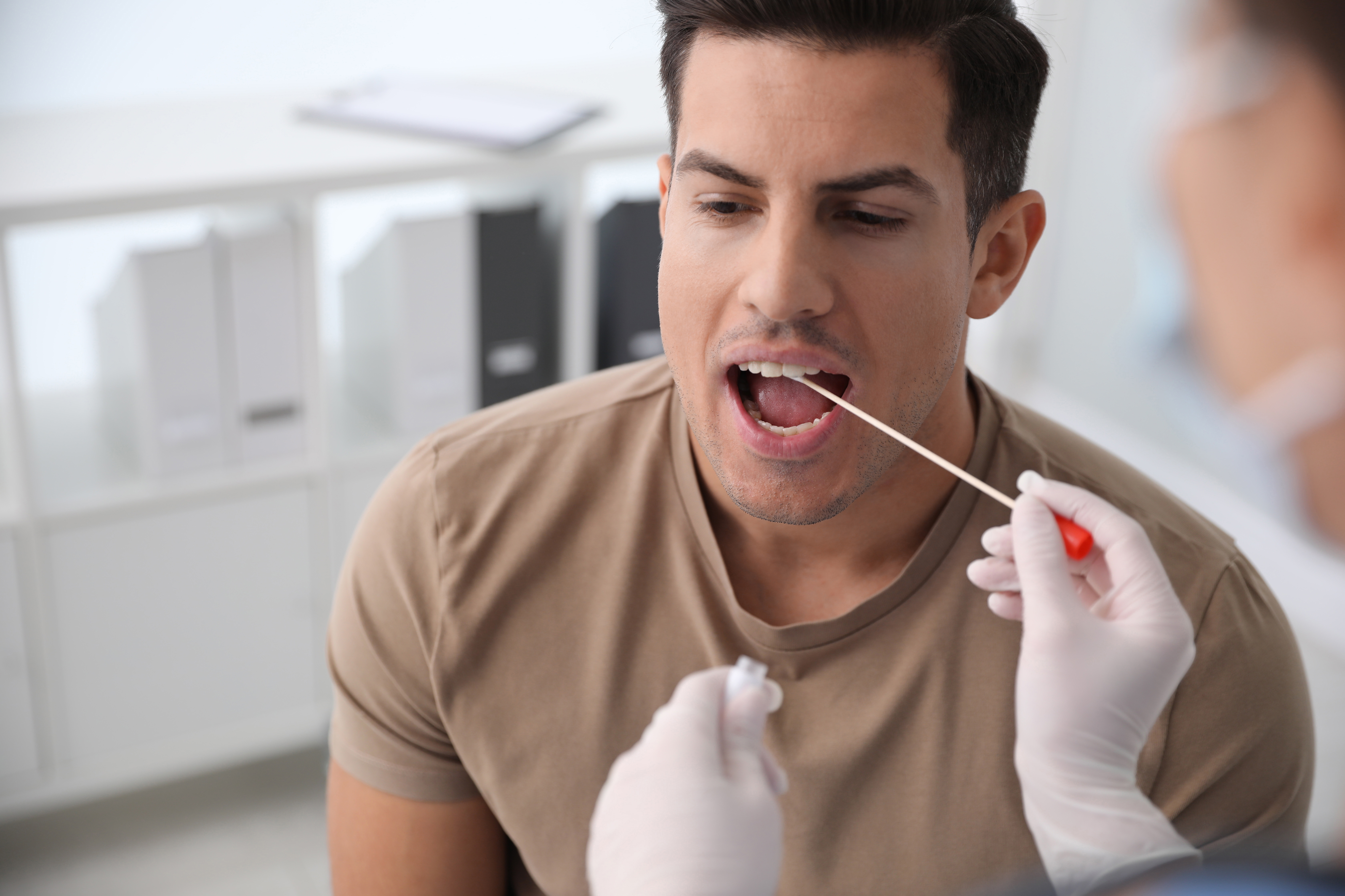 Arzt, der einem Mann in der Klinik eine Probe für einen DNA-Test entnimmt | Quelle: Shutterstock