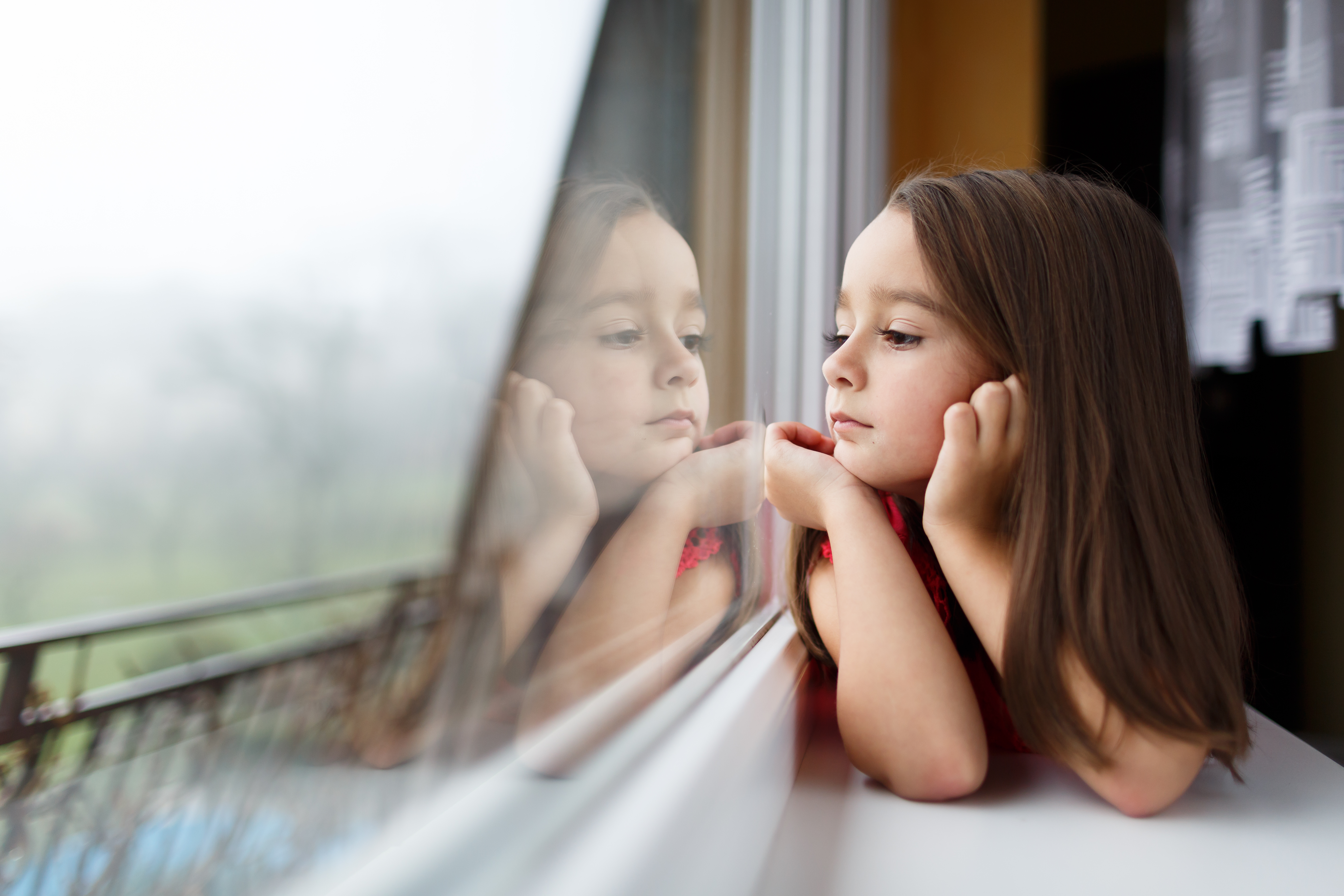 Kleines Mädchen schaut aus dem Fenster | Quelle: Shutterstock