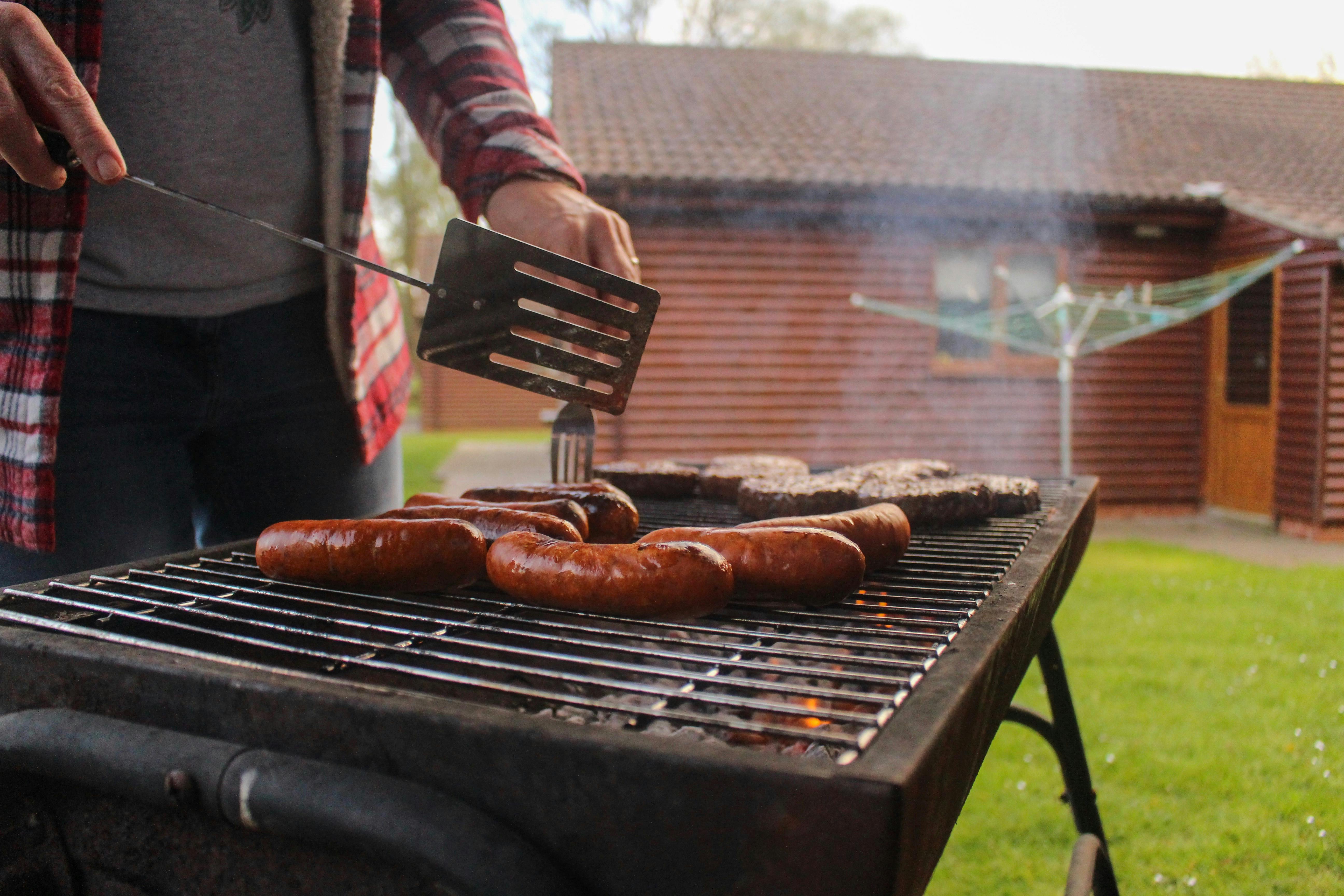 Eine Person beim Grillen von Würstchen | Quelle: Pexels