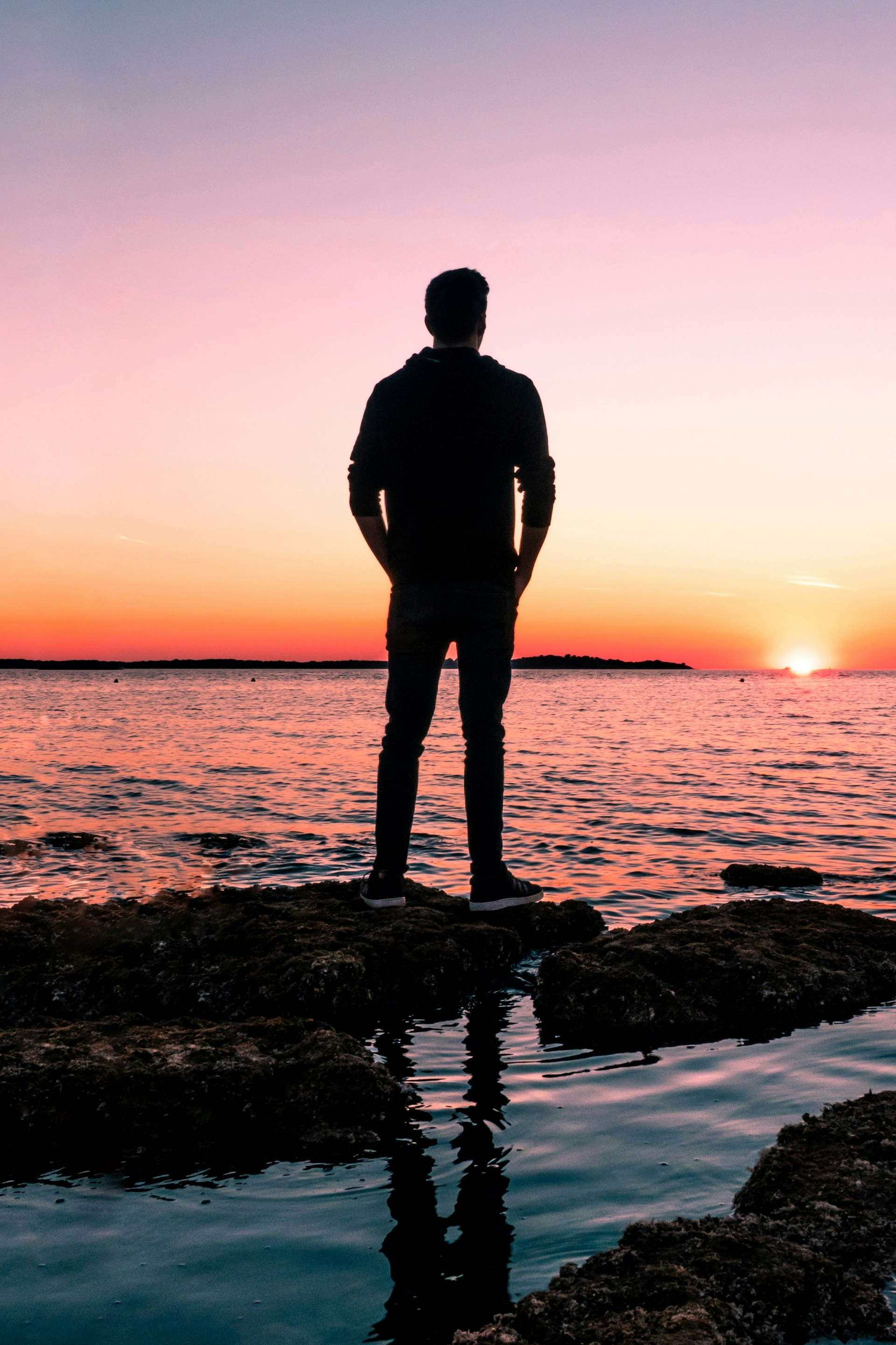 Ein Mann, der an einem malerischen Abend das goldene Sonnenlicht vom Ufer aus betrachtet | Quelle: Unsplash