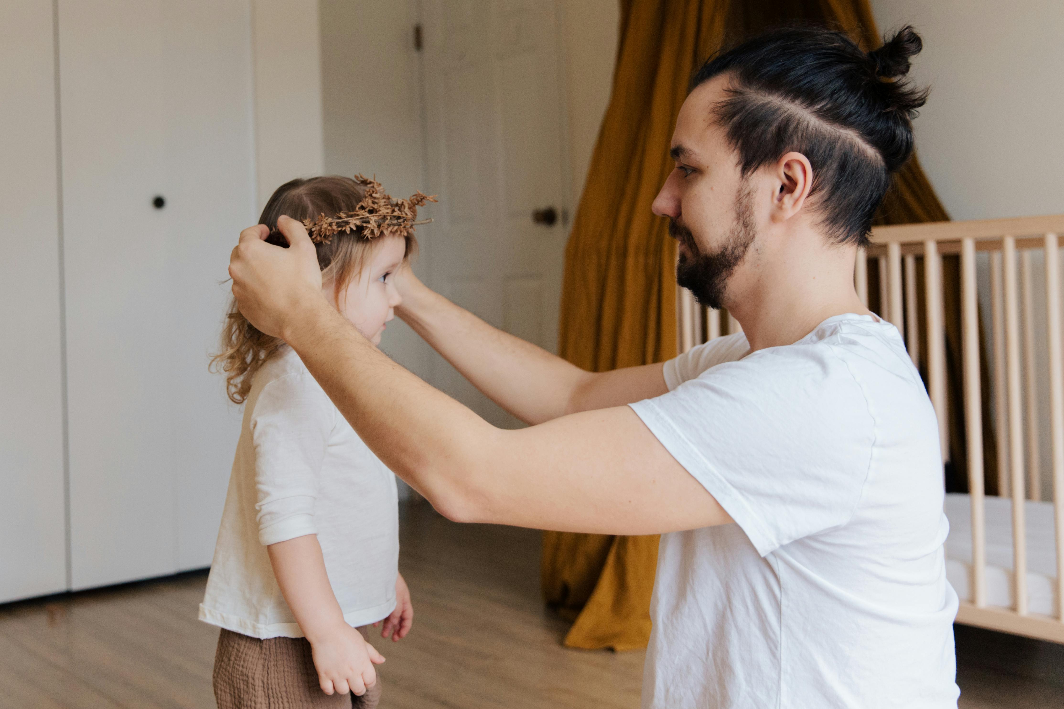 Ein Vater schmückt die Haare seiner Tochter | Quelle: Pexels