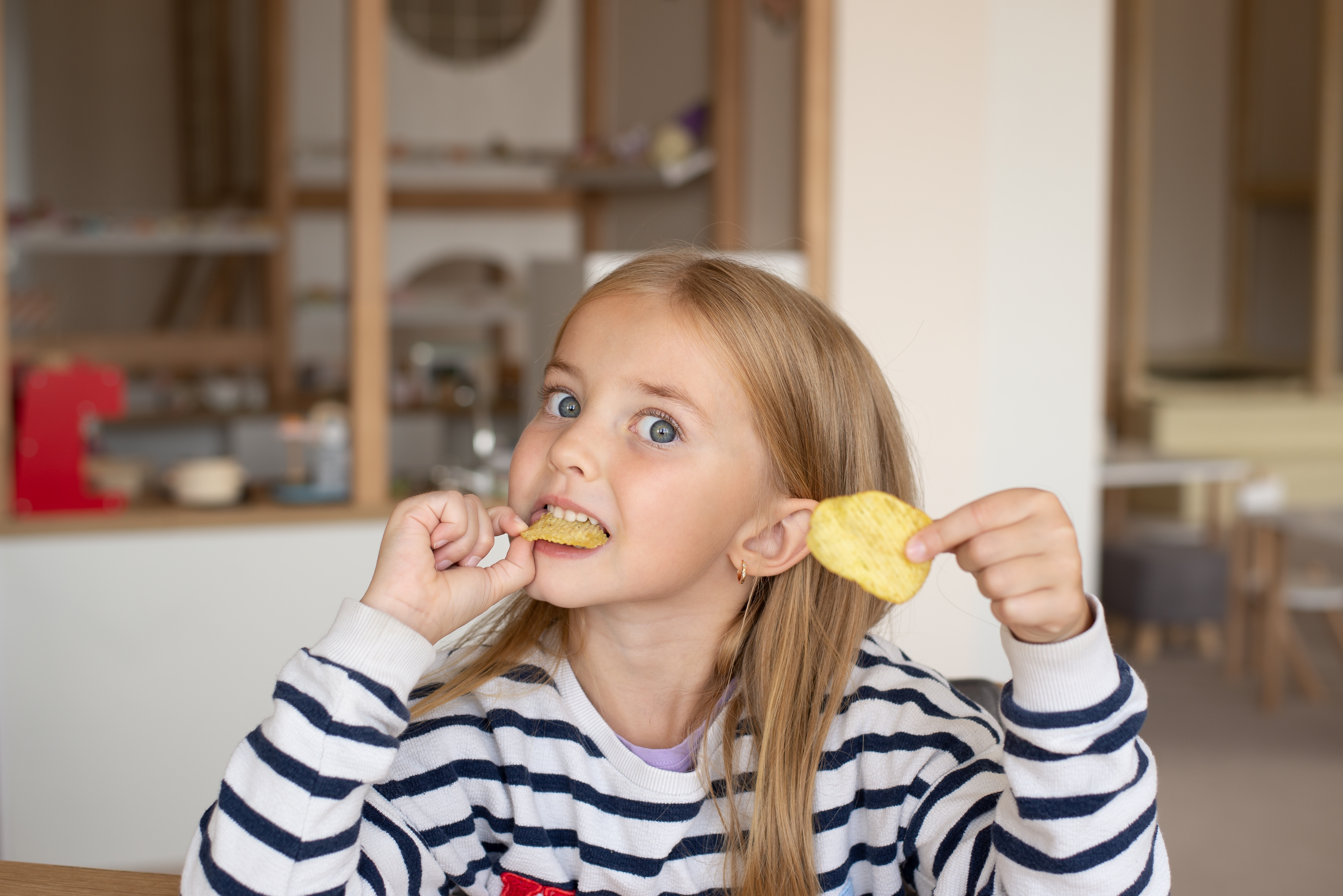 Ein kleines Mädchen isst Kartoffelchips | Quelle: Shutterstock