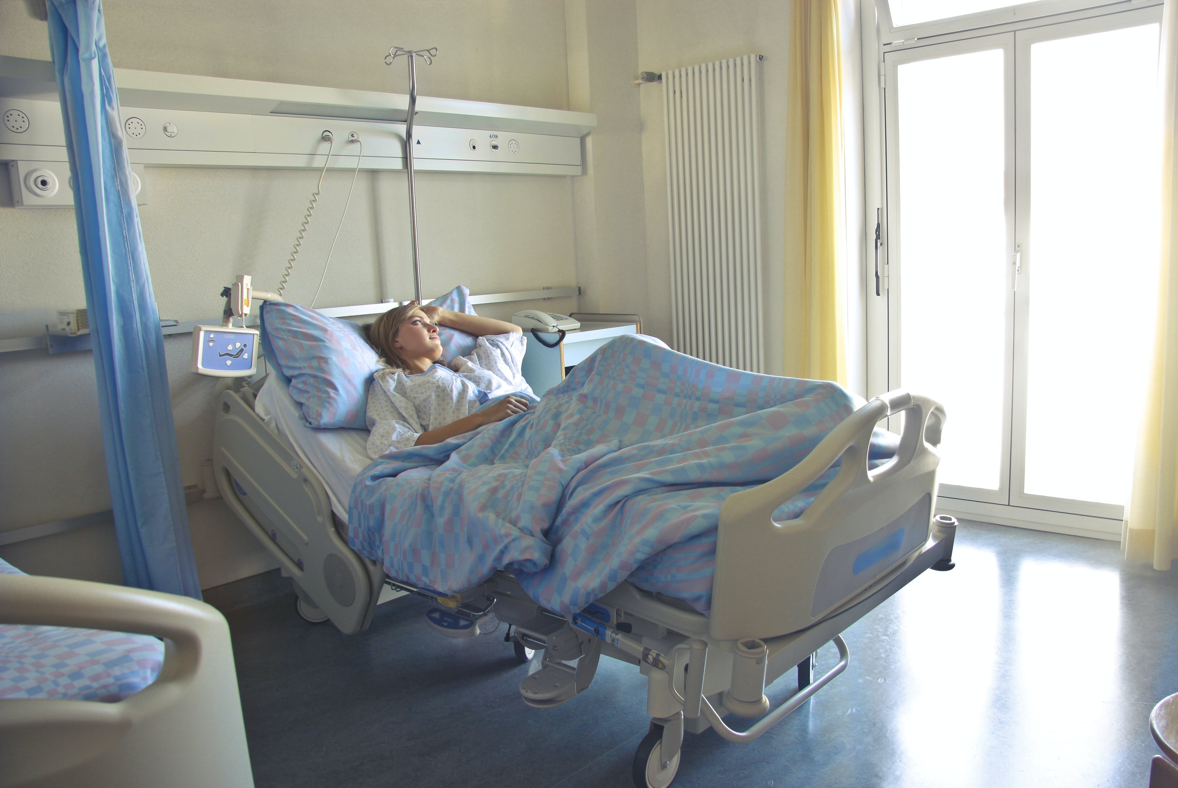 Eine Frau liegt auf einem Krankenhausbett allein in ihrem Zimmer | Quelle: Pexels
