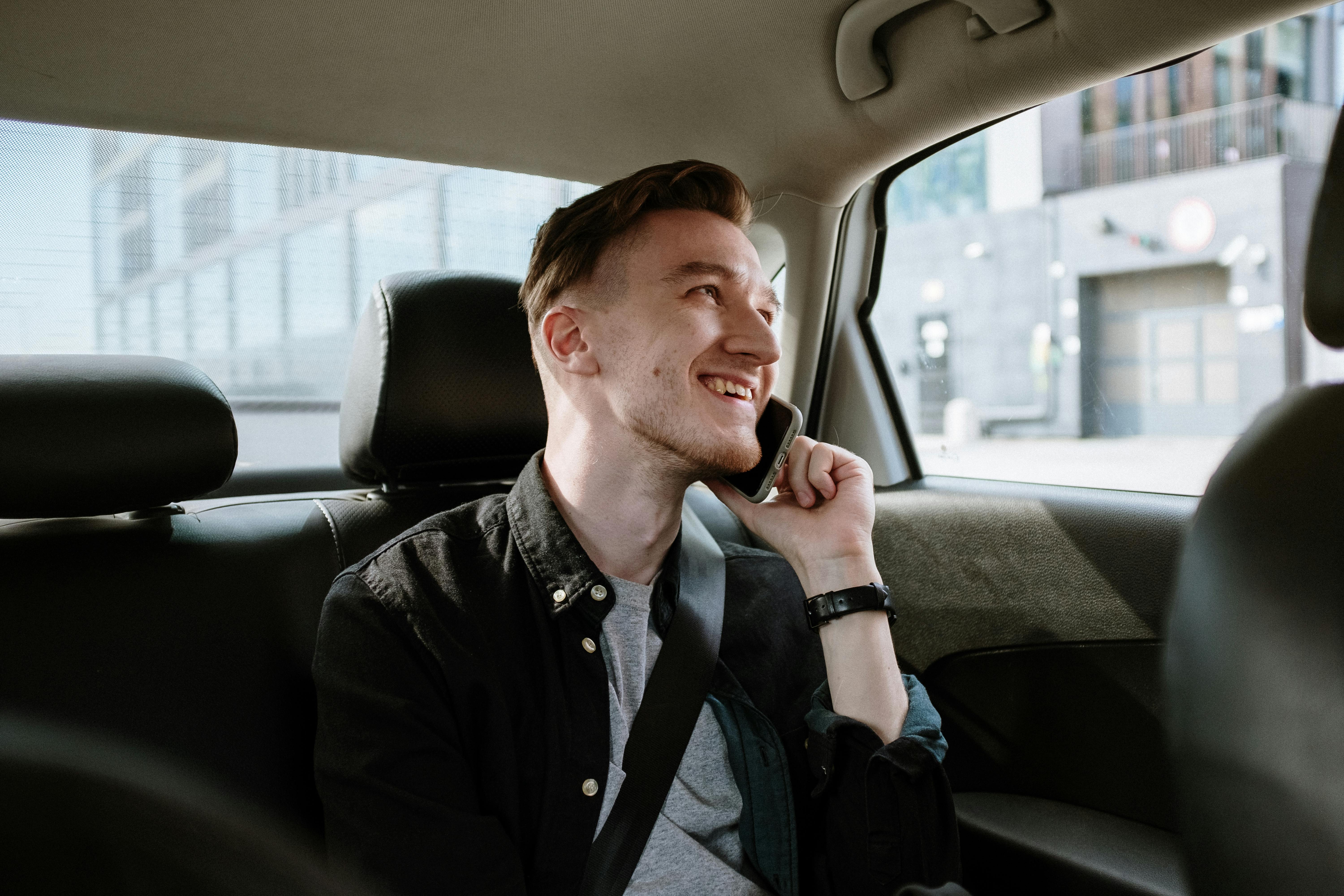 Ein glücklicher Mann, der während der Fahrt im Auto telefoniert | Quelle: Pexels