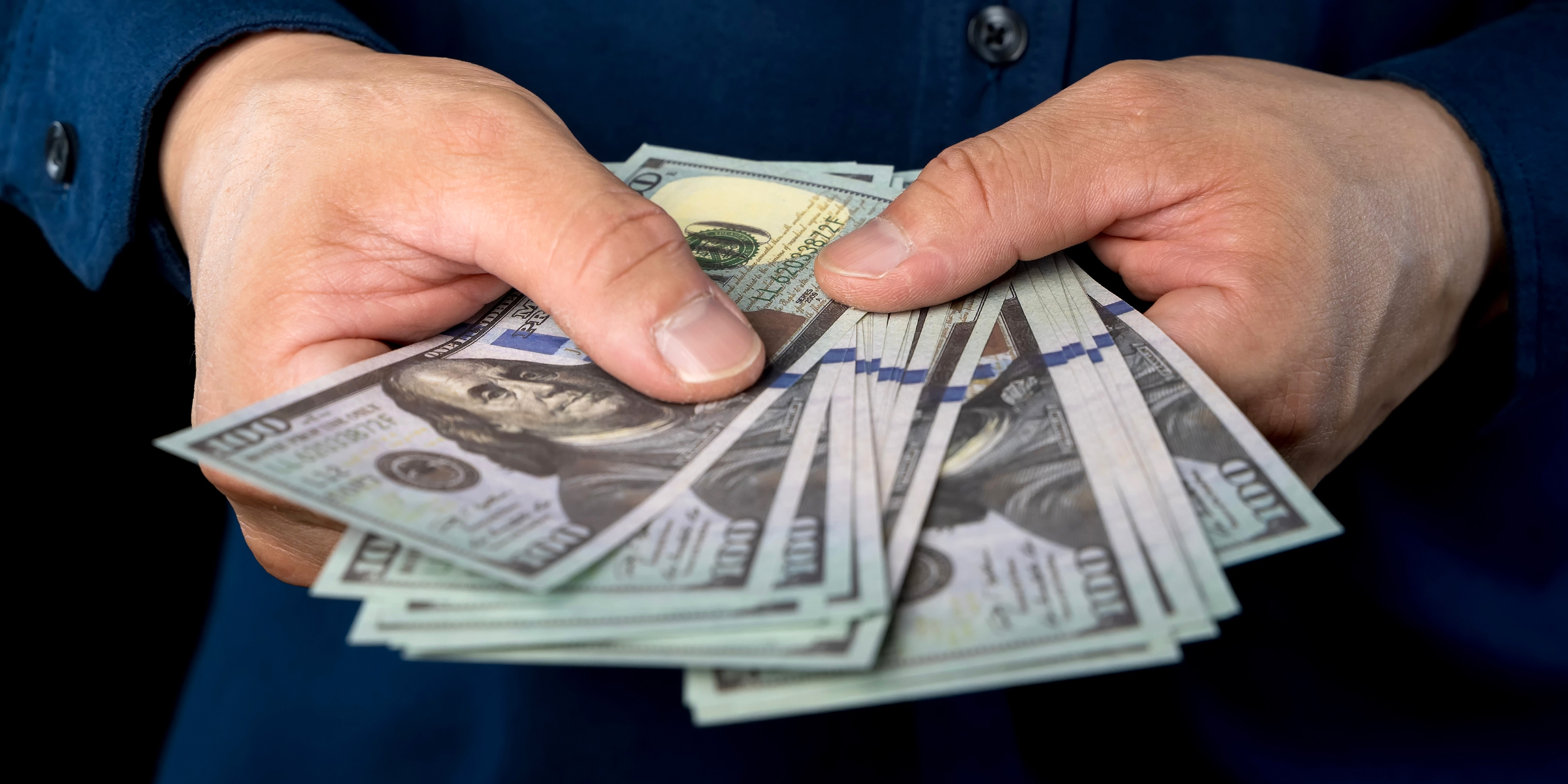 Eine Person mit Dollarscheinen in der Hand | Quelle: Shutterstock