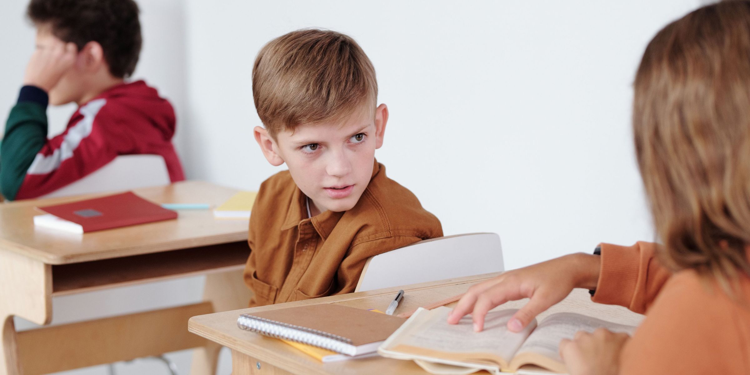 Ein kleiner Junge sitzt in einem Klassenzimmer | Quelle: Pexels