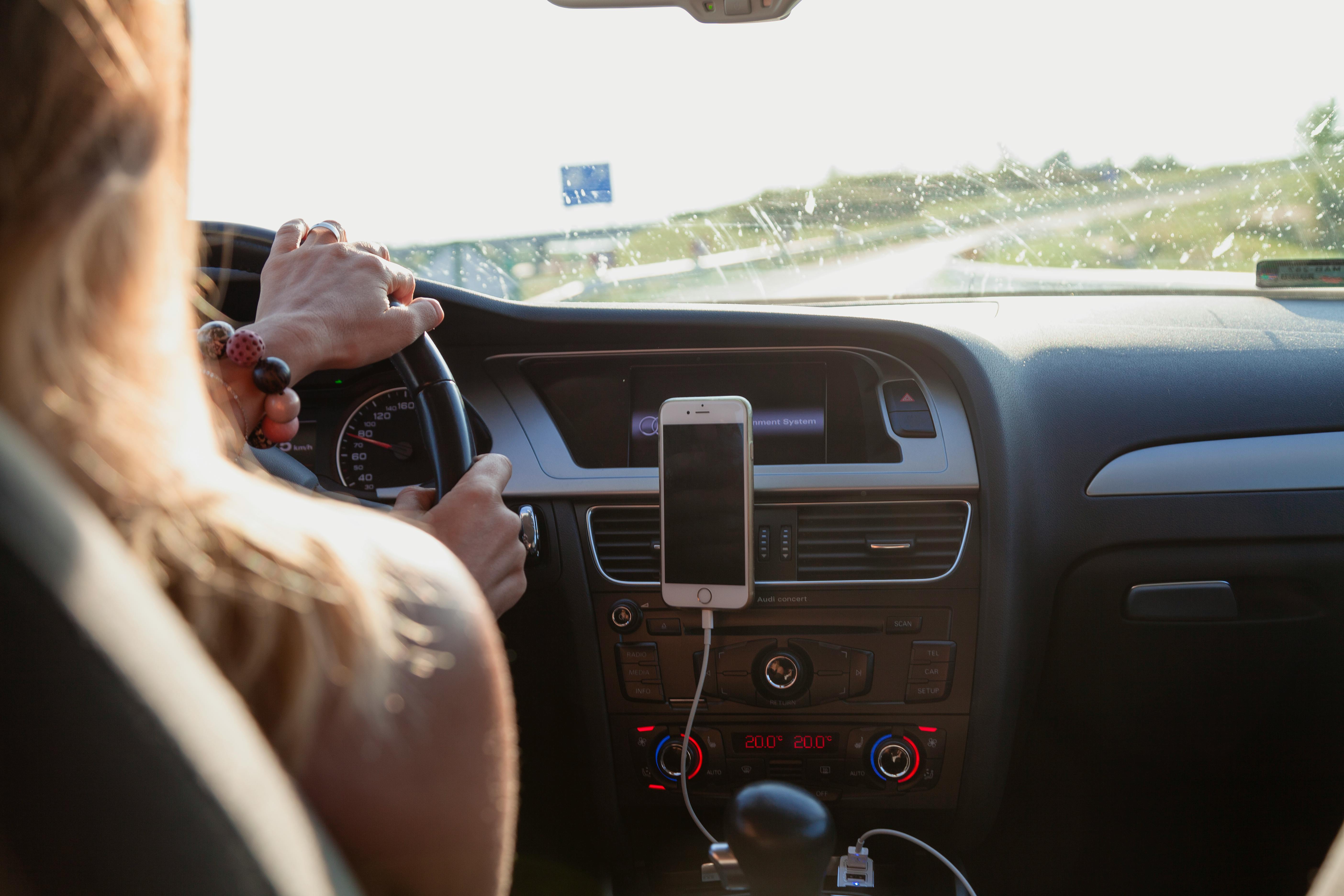 Eine Frau fährt mit ihrem angedockten Telefon im Auto | Quelle: Pexels