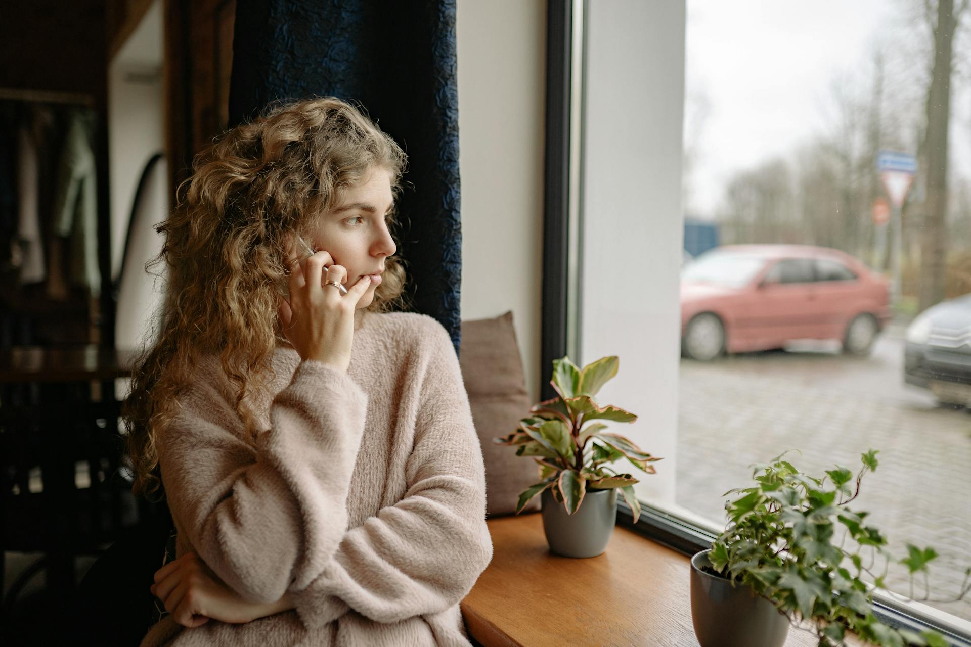 Eine Frau telefoniert, während sie durch das Fenster schaut | Quelle: Pexels