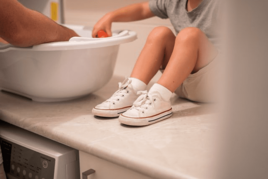 Kind sitzt neben dem Waschbecken. | Quelle: Unsplash