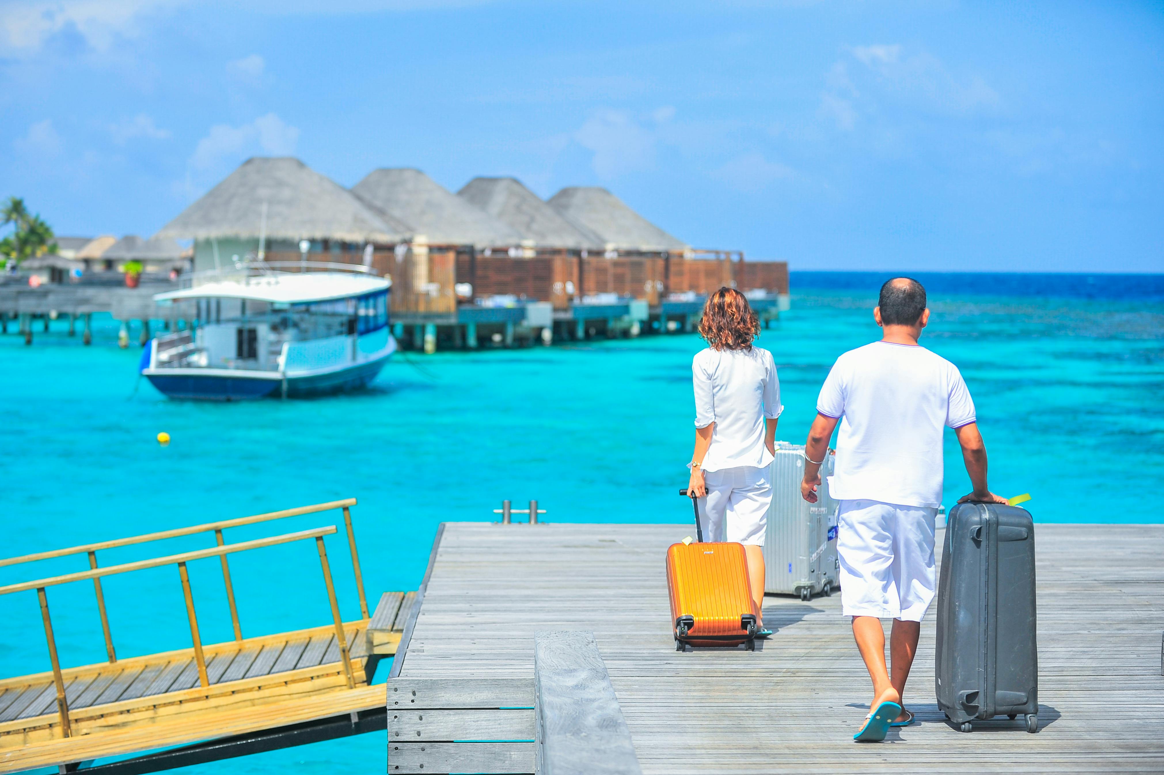 Ein Mann und eine Frau gehen mit Koffern auf dem Steg spazieren | Quelle: Pexels