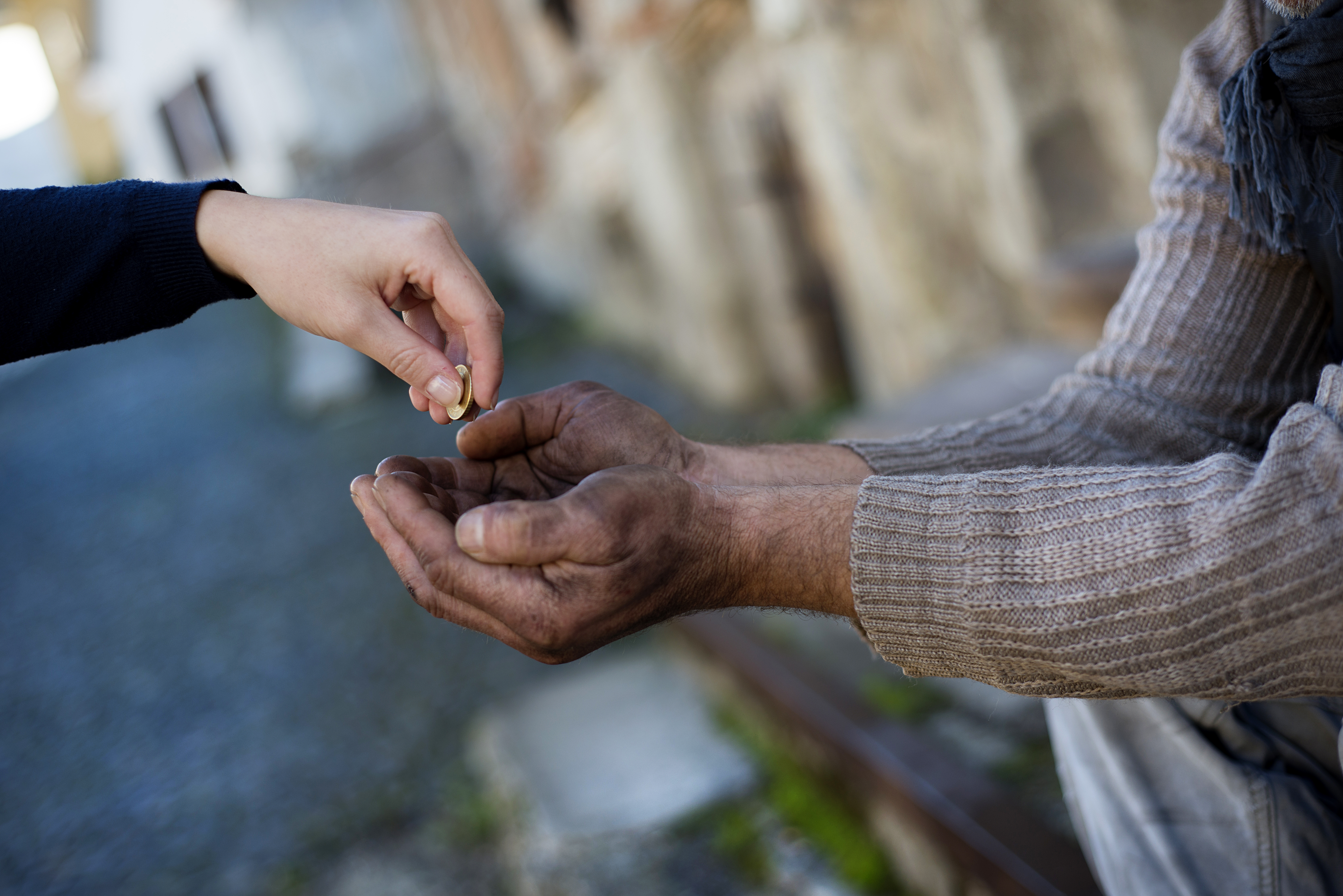 Jemand gibt einem Obdachlosen Kleingeld. | Quelle: Shutterstock