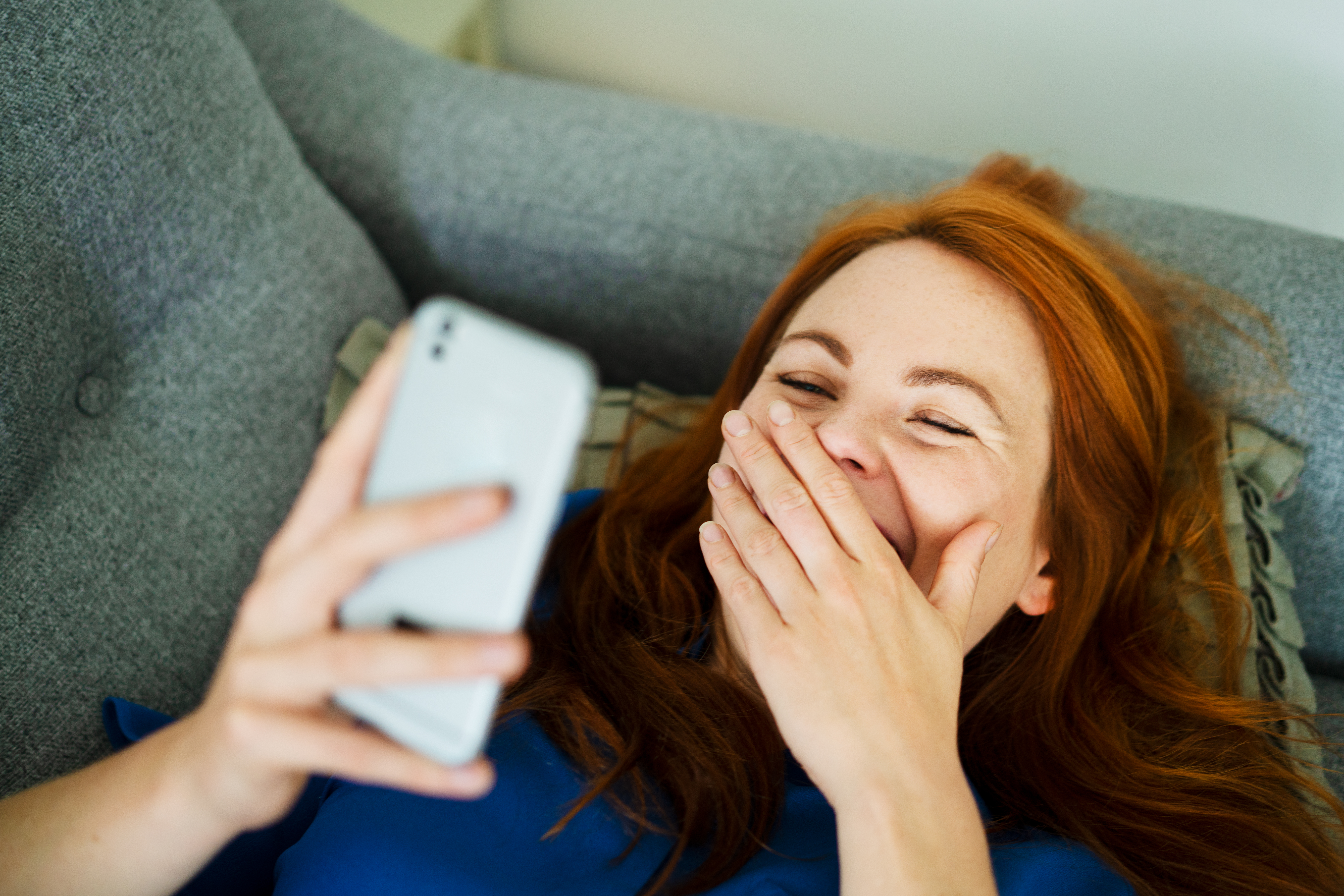 Eine Frau lacht, während sie auf ihr Telefon schaut | Quelle: Getty Images