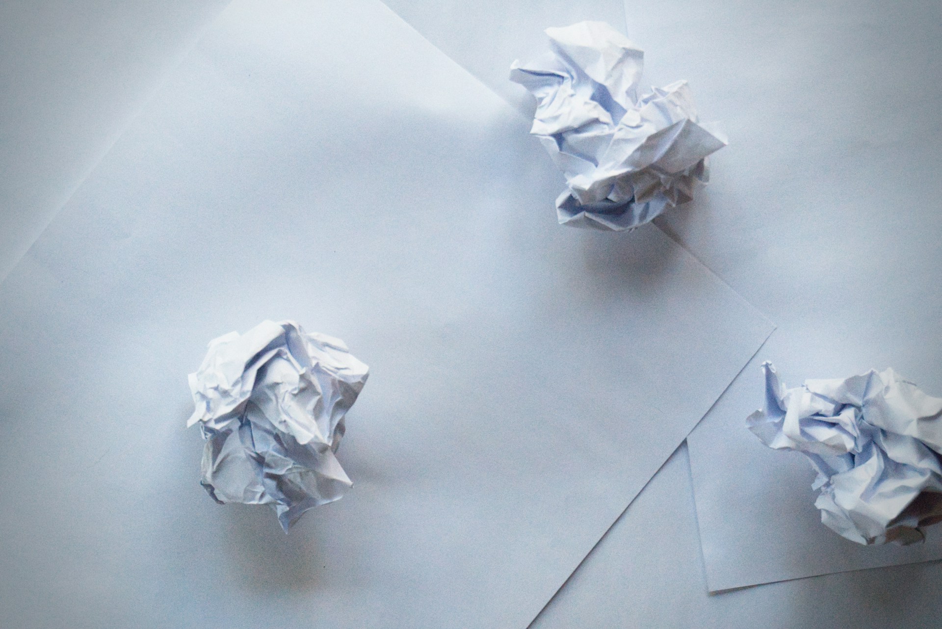 Zerknüllte Papierkugeln und Papierbögen auf einer Fläche | Quelle: Unsplash