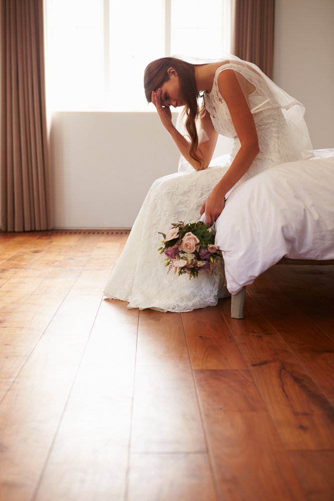 Eine besorgte Braut sitzt mit einem Blumenstrauß in der Hand. | Quelle: Shutterstock