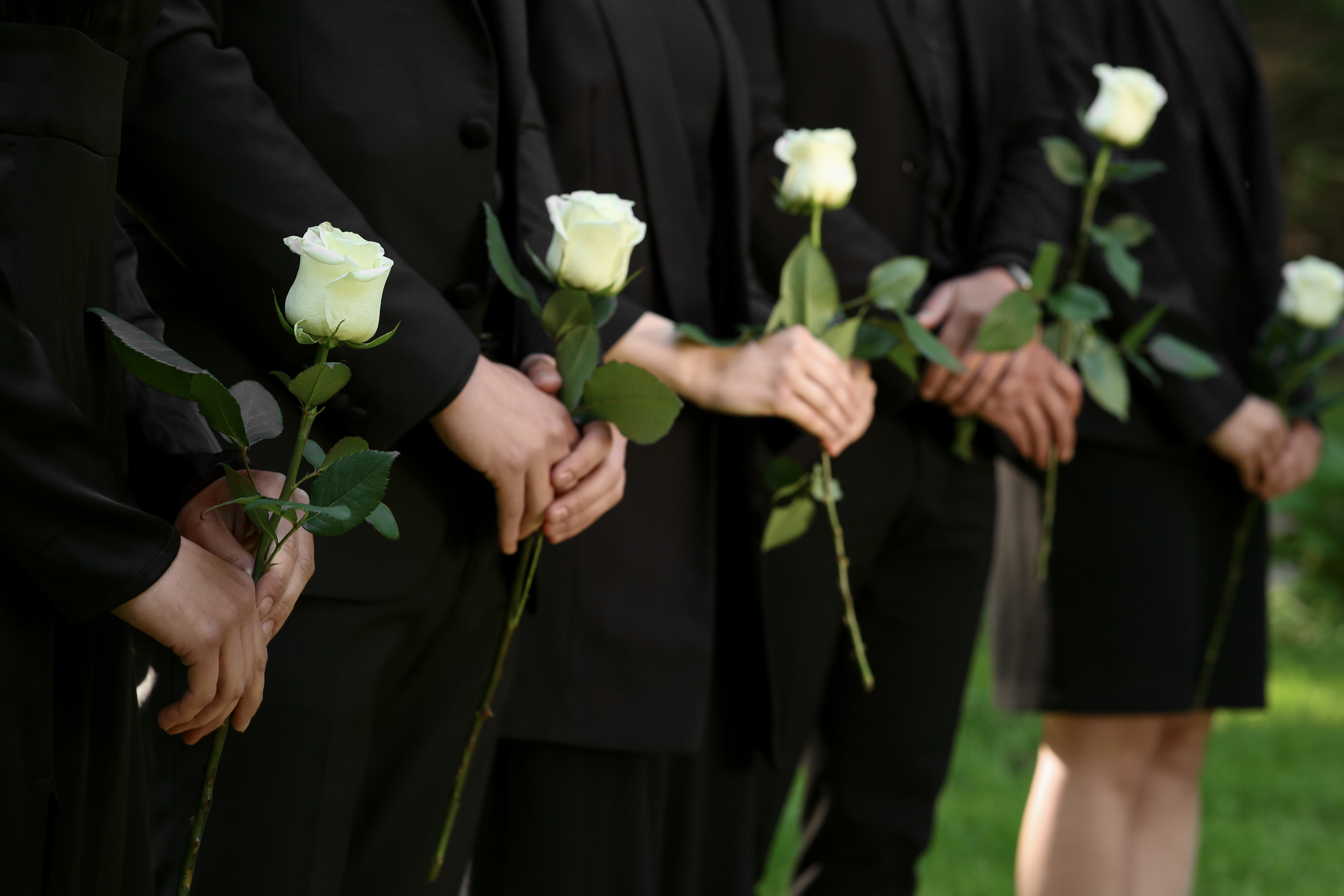 Eine Familie hält Rosen bei einer Beerdigung | Quelle: Shutterstock