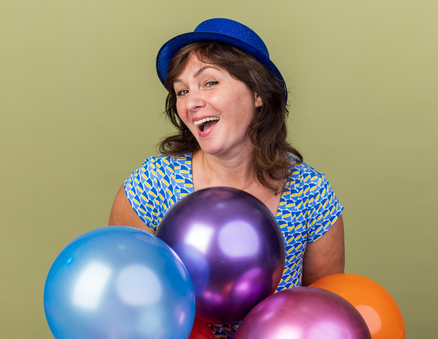 Eine fröhliche Frau mittleren Alters hält bunte Luftballons | Quelle: Freepik