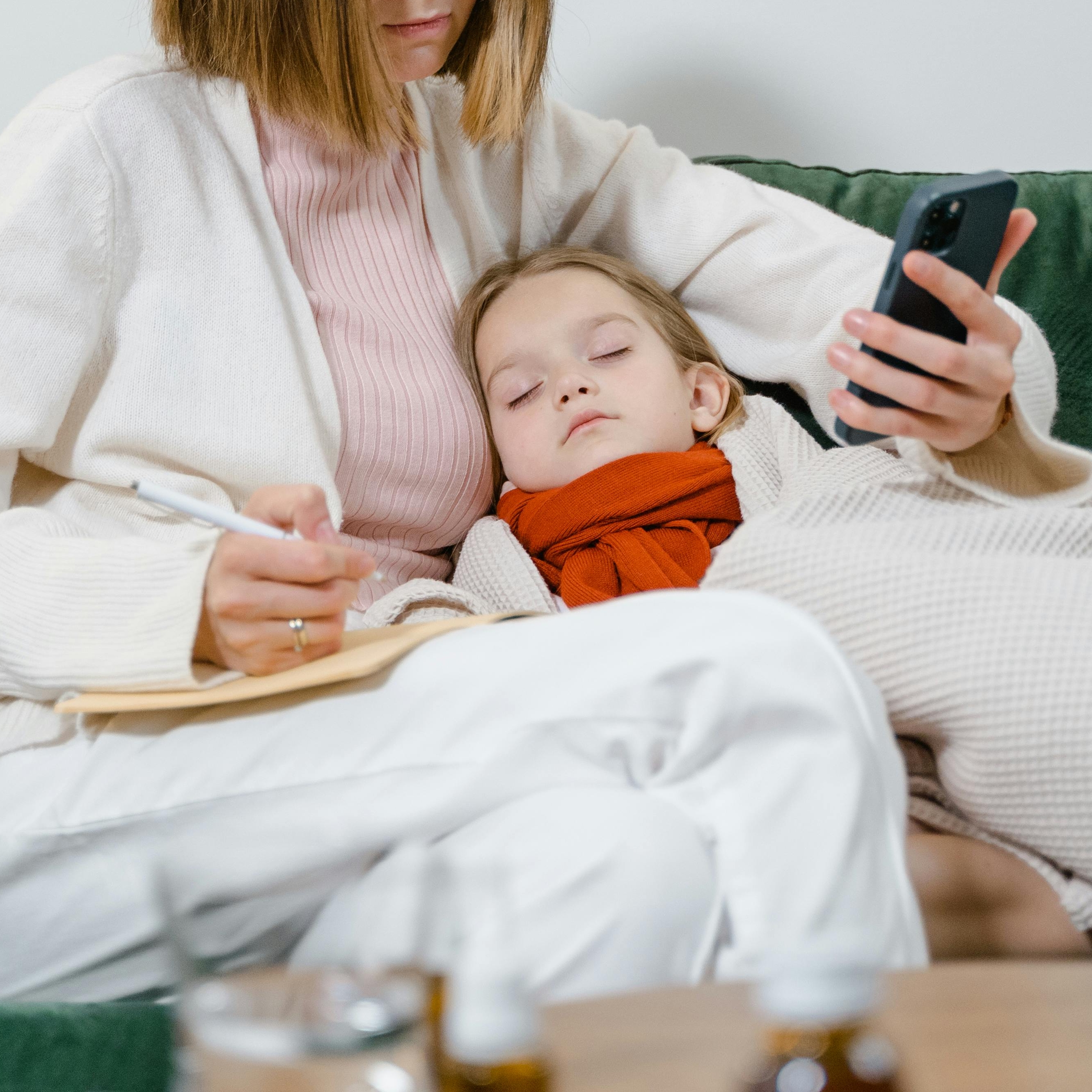 Eine Frau kümmert sich um ein krankes Kind, während sie Notizen macht | Quelle: Pexels