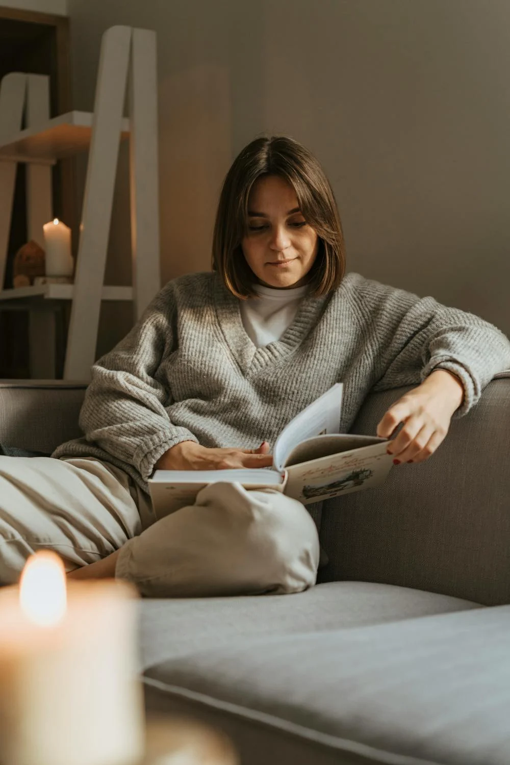 Eine Frau liest ein Buch auf einer Couch | Quelle: Pexels