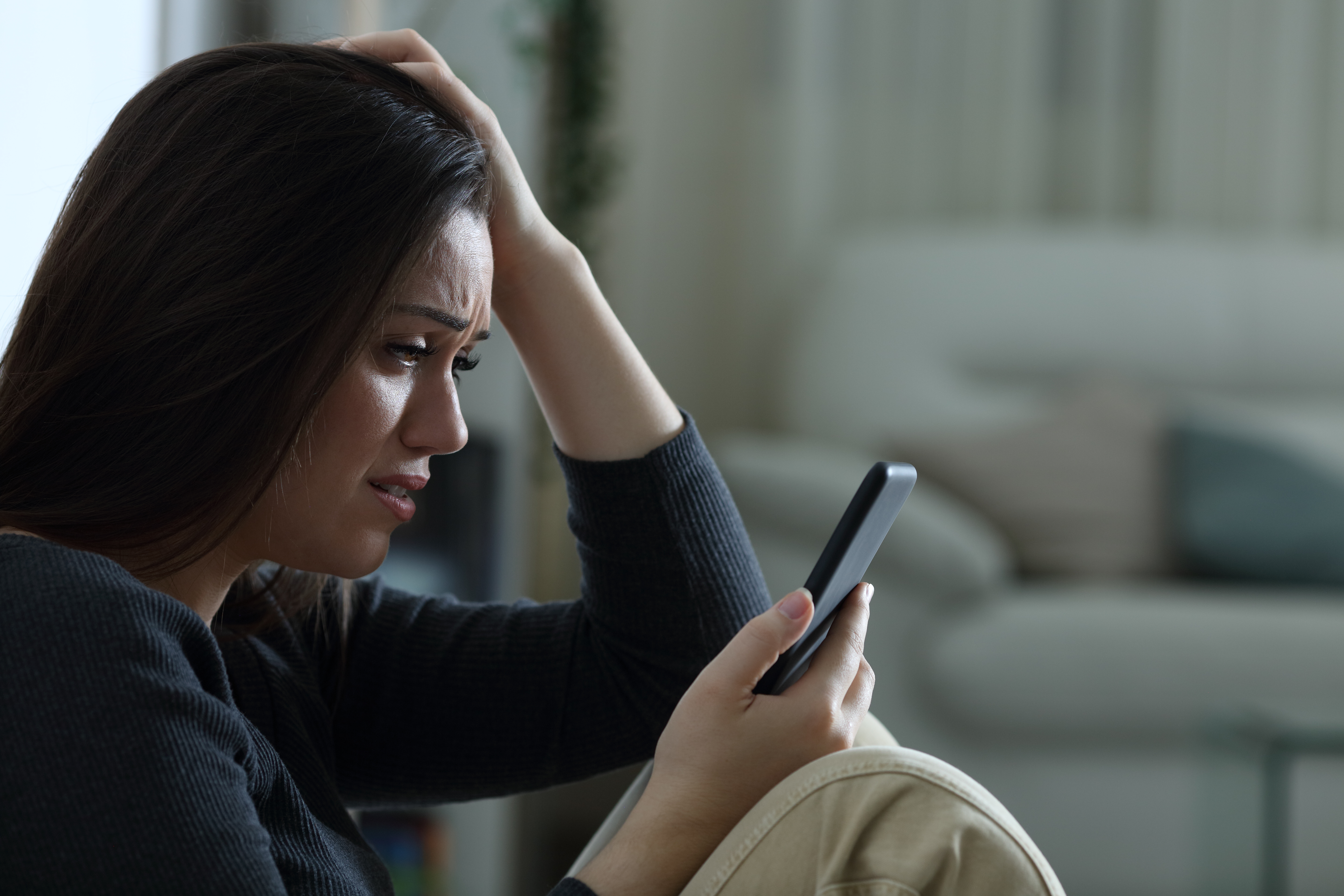 Eine traurige Frau schaut auf ihr Telefon | Quelle: Shutterstock