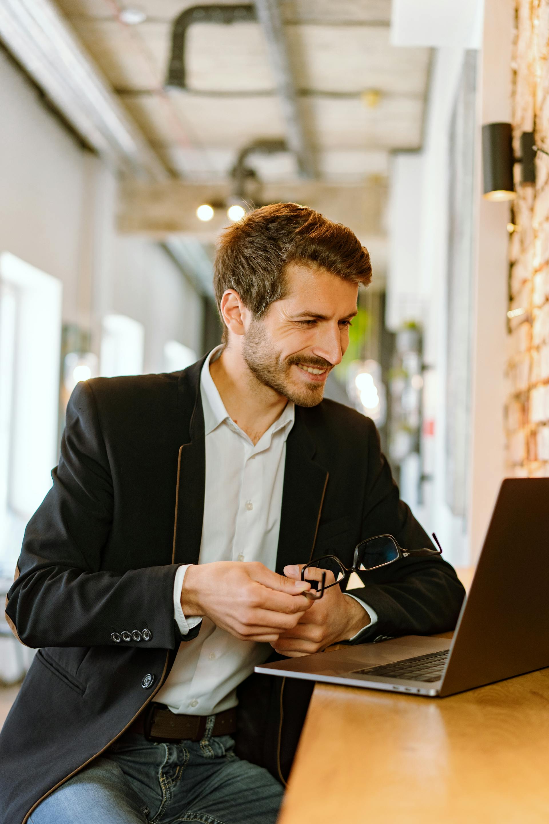 Ein Mann im Anzug lächelt, während er auf seinen Laptop schaut | Quelle: Pexels