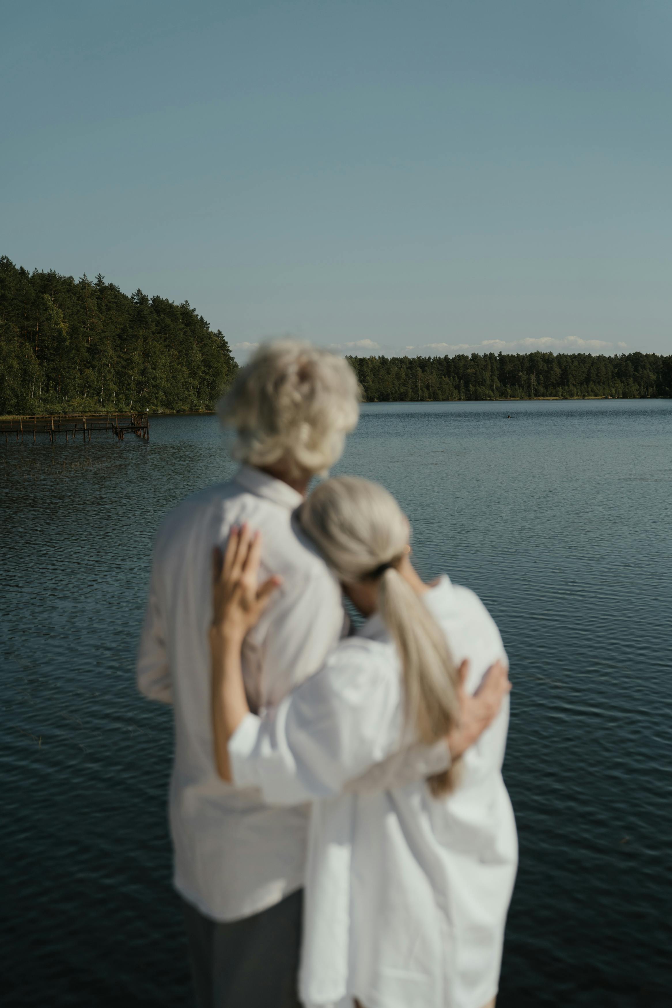 Ein älteres Paar umarmt sich mit Blick auf einen See | Quelle: Pexels