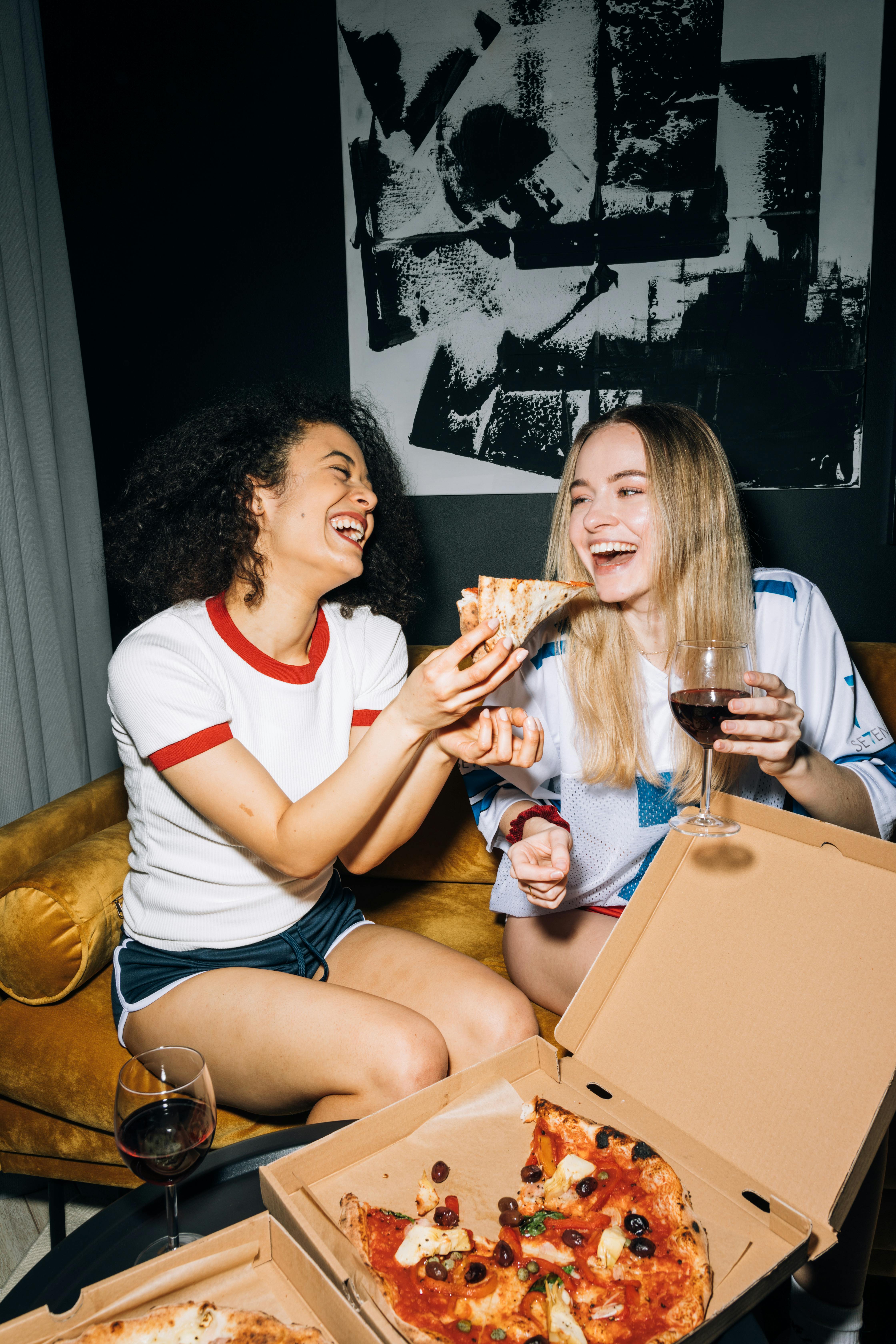 Frauen, die Pizza und Wein genießen | Quelle: Pexels