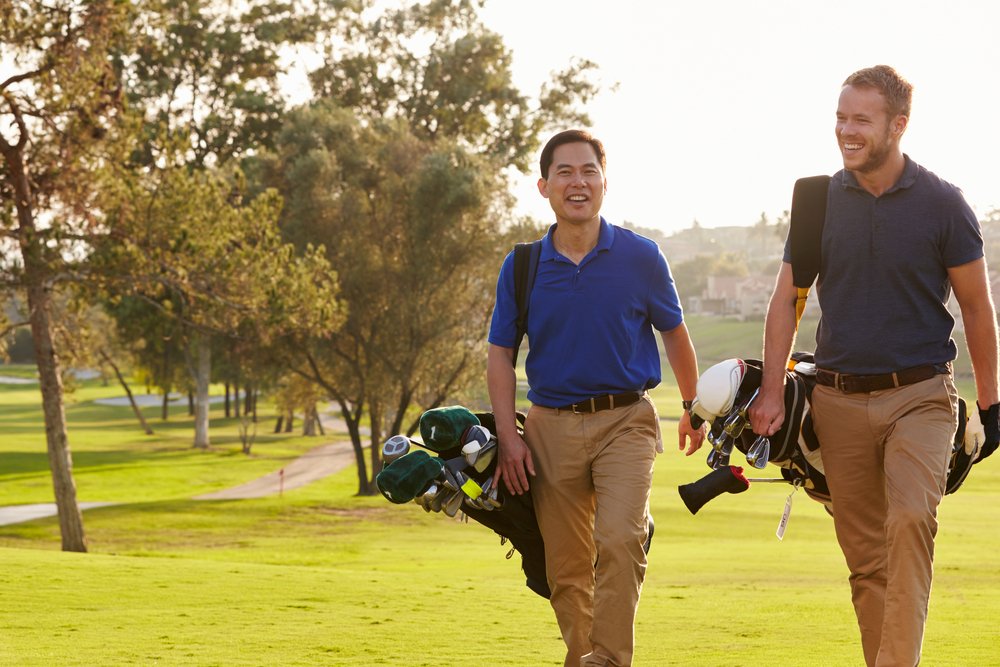 Zwei männliche Golfer beim Spaziergang auf dem Golfplatz. | Quelle: Shutterstock