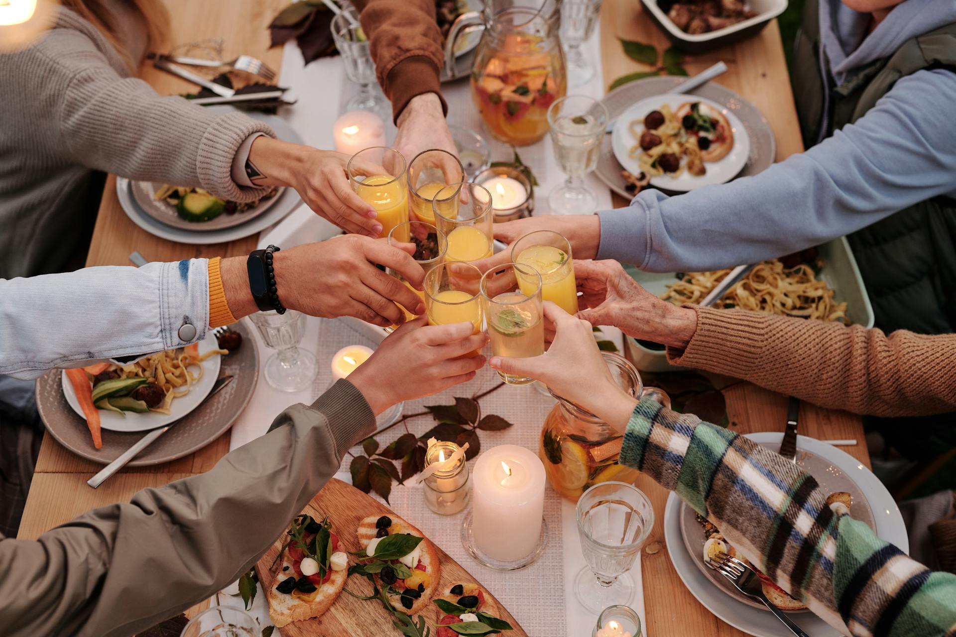 Eine Nahaufnahme von Familienmitgliedern, die beim Abendessen anstoßen | Quelle: Pexels