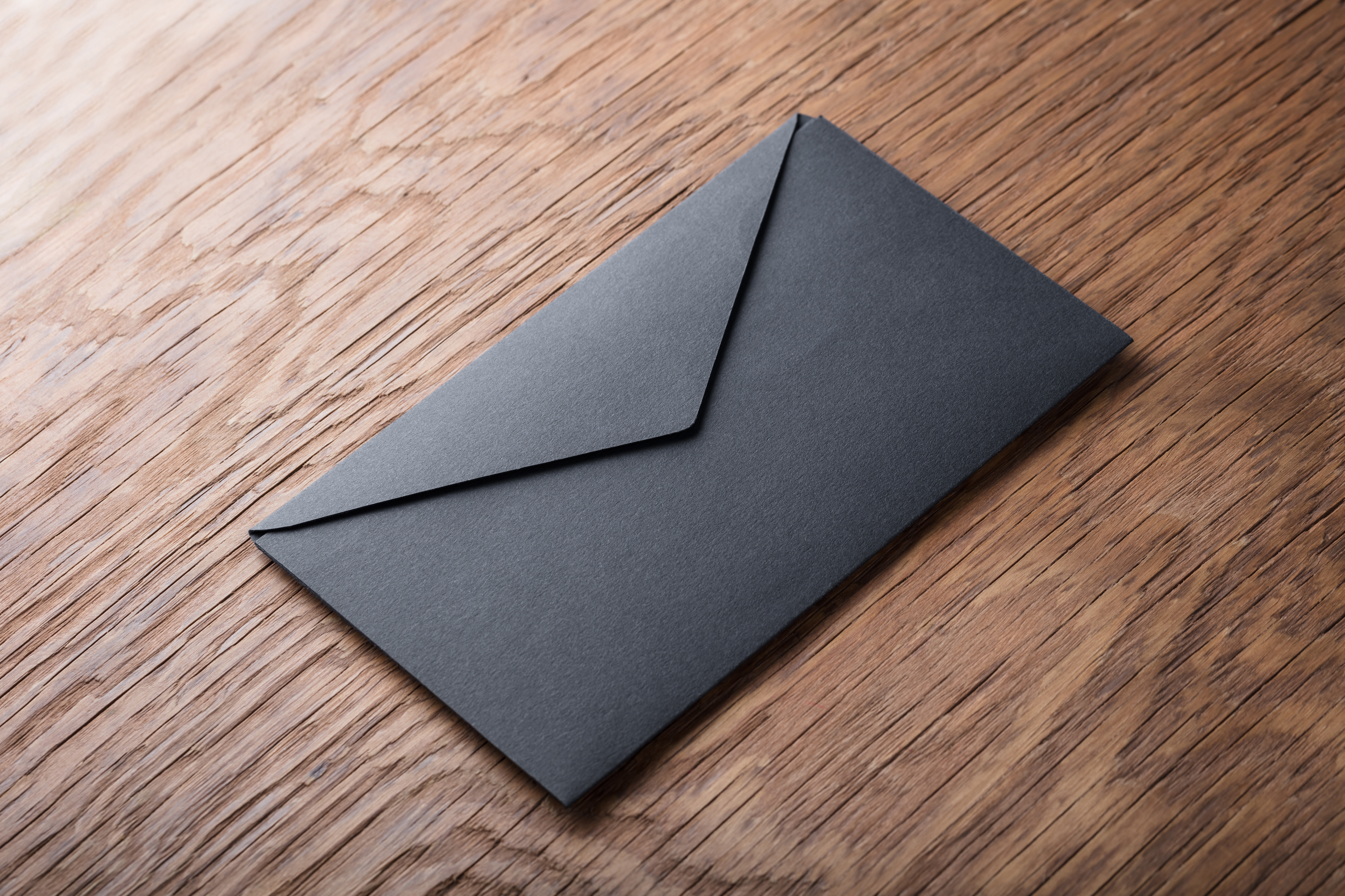 Schwarzer Umschlag auf Holztisch | Quelle: Shutterstock