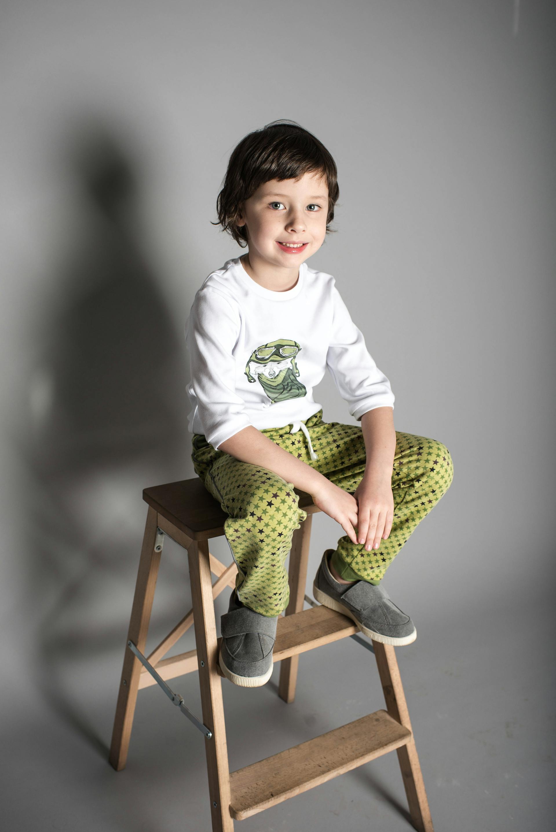 Ein lächelnder kleiner Junge sitzt auf einem Hocker | Quelle: Pexels