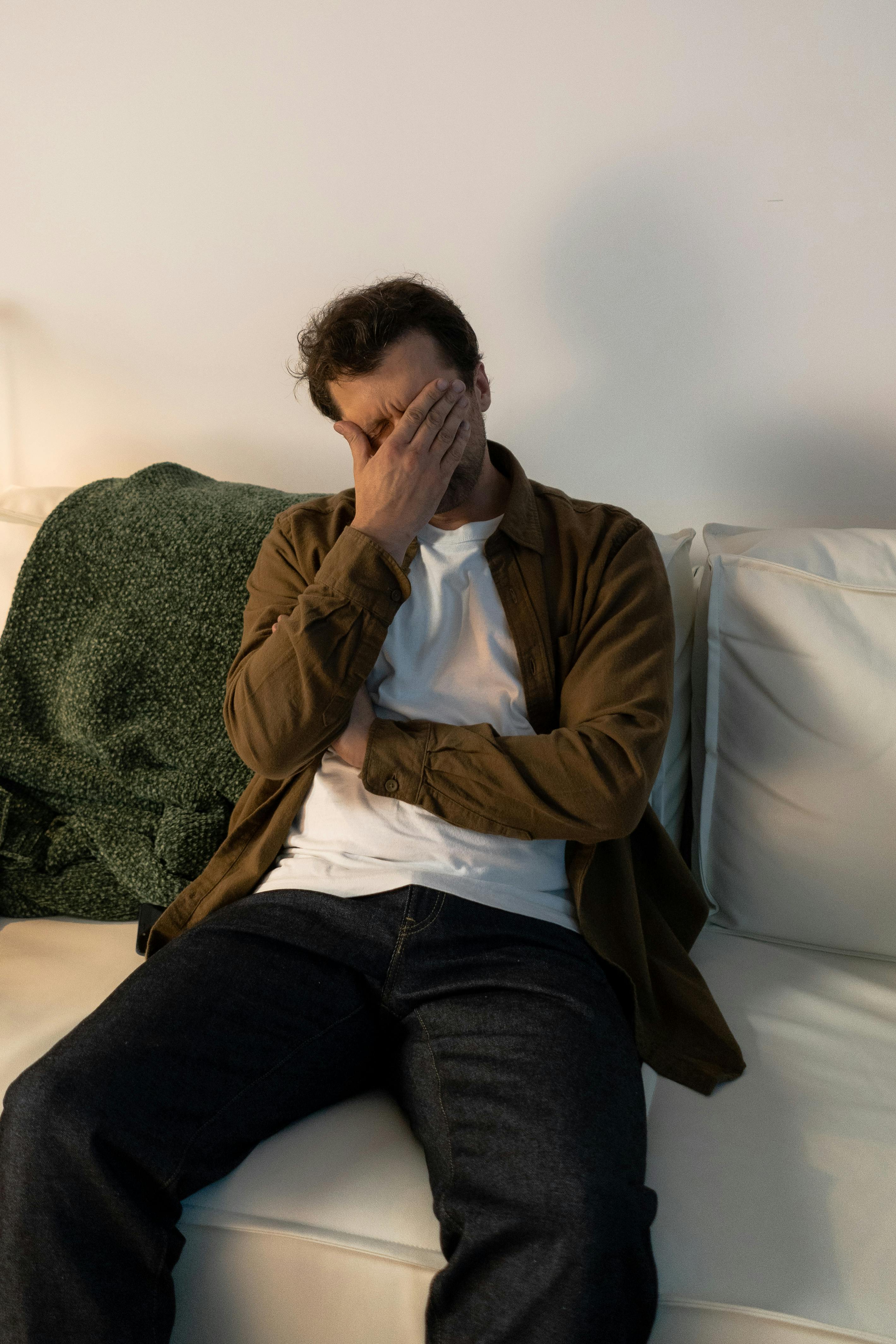 Ein verzweifelter Mann sitzt auf einer Couch | Quelle: Pexels
