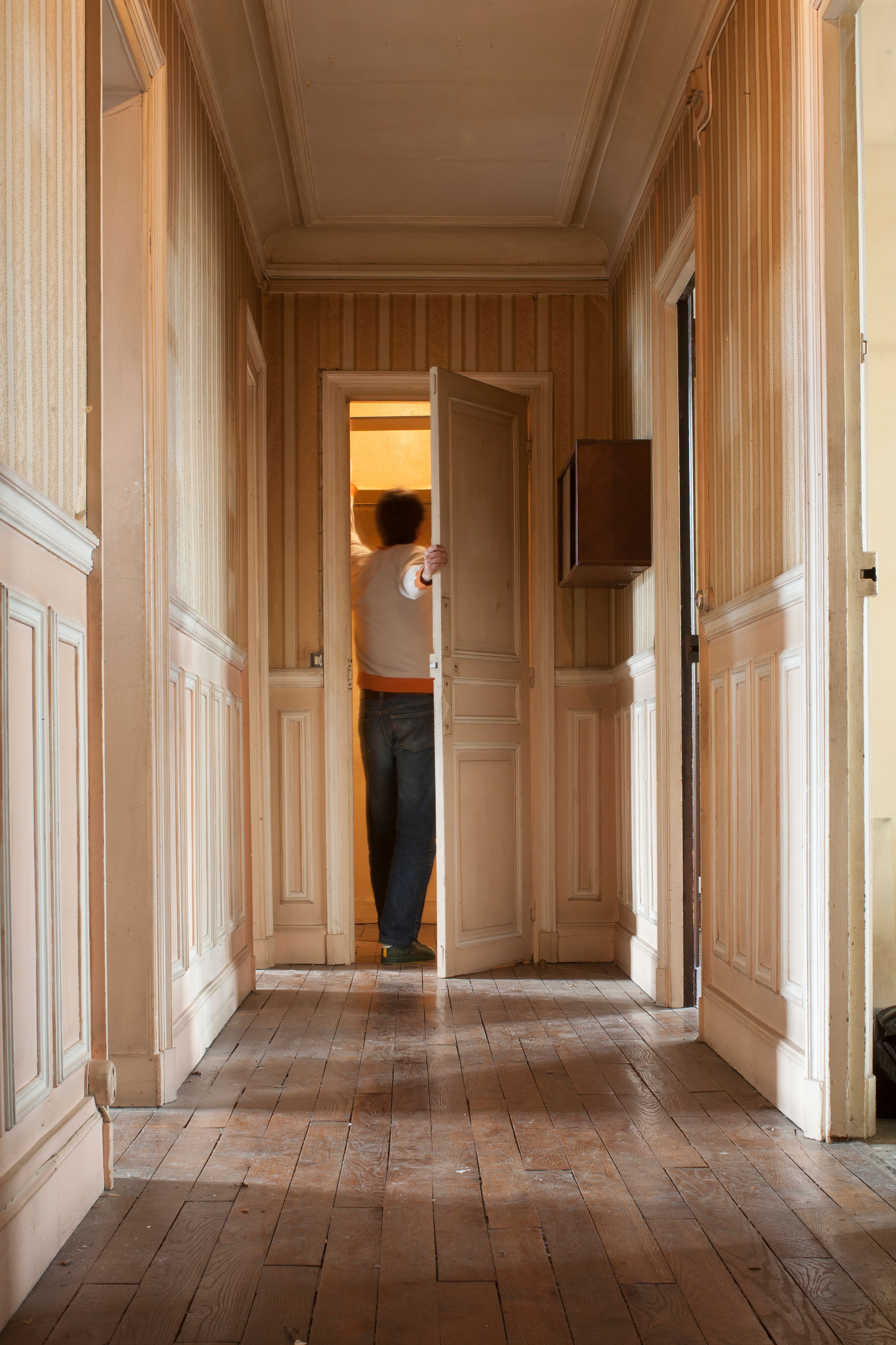 Ein Mann öffnet eine Tür in einem Flur. | Quelle: Getty Images