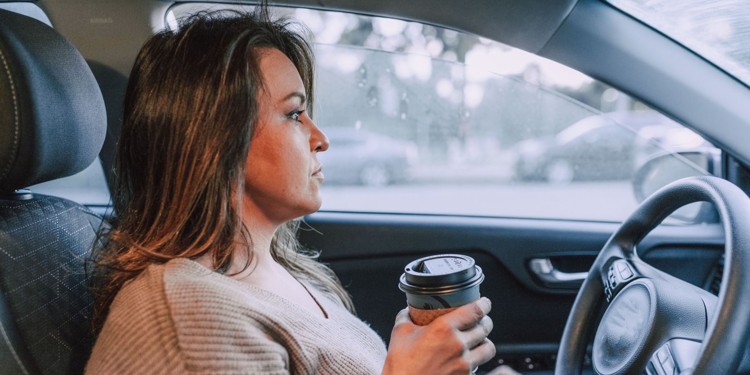 Eine Frau, die Auto fährt und eine Kaffeetasse in der Hand hält | Quelle: Pexels