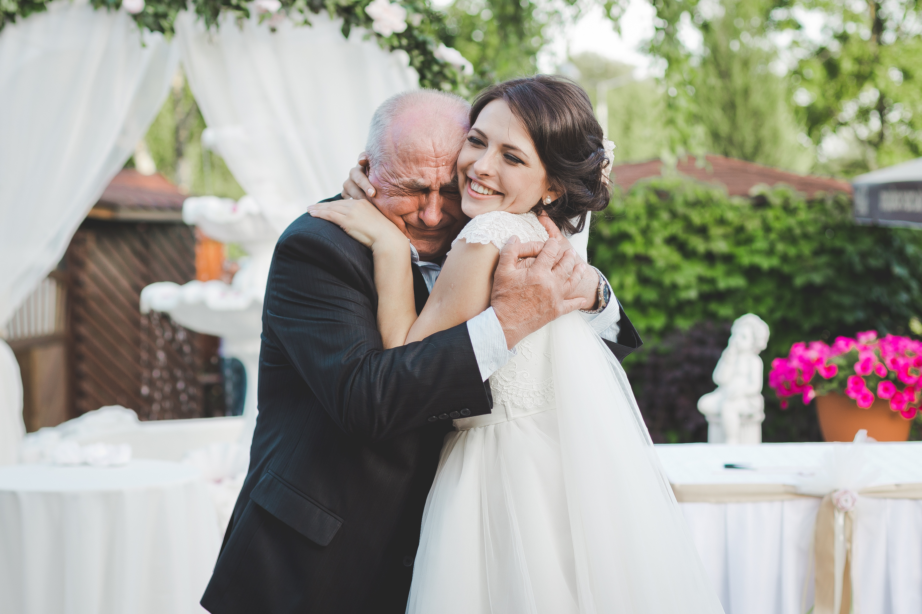 Die Braut lächelt, während sie einen älteren Mann umarmt. | Quelle: Shutterstock