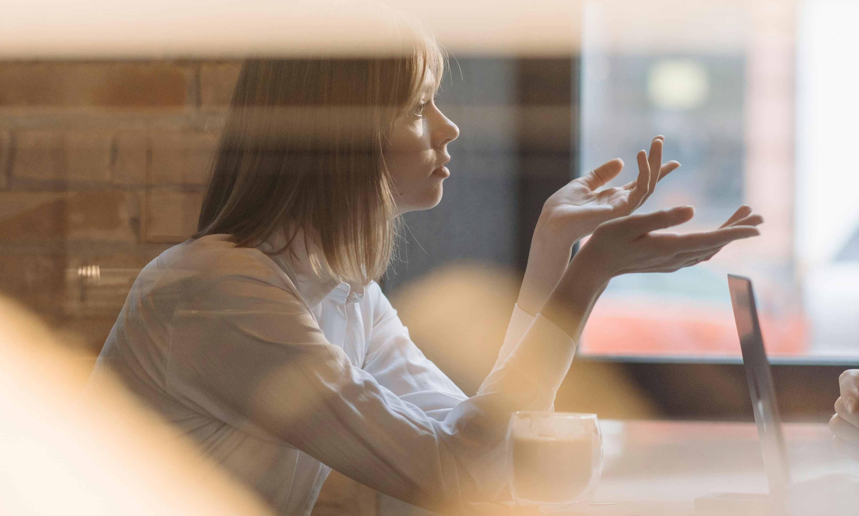 Eine Frau in einem Café, die mit ihren Händen gestikuliert | Quelle: Pexels