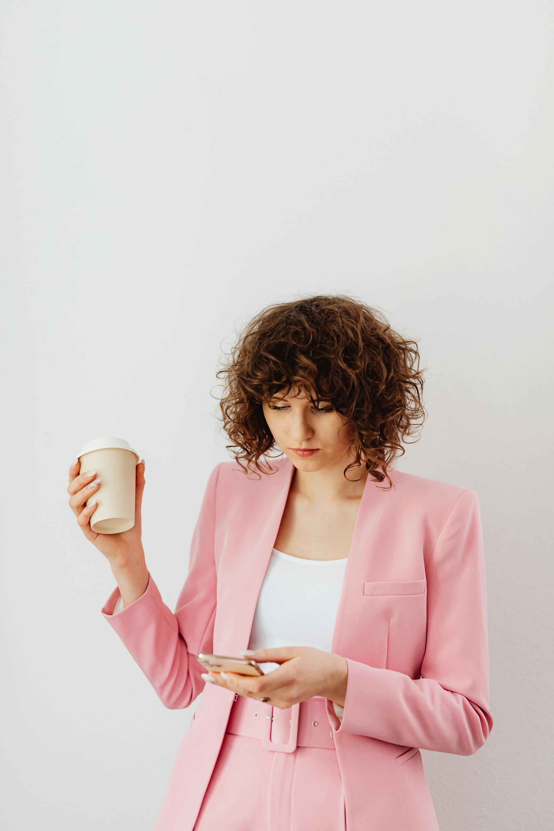 Eine entschlossene Frau, die einen Kaffee und ein Telefon in der Hand hält | Quelle: Pexels