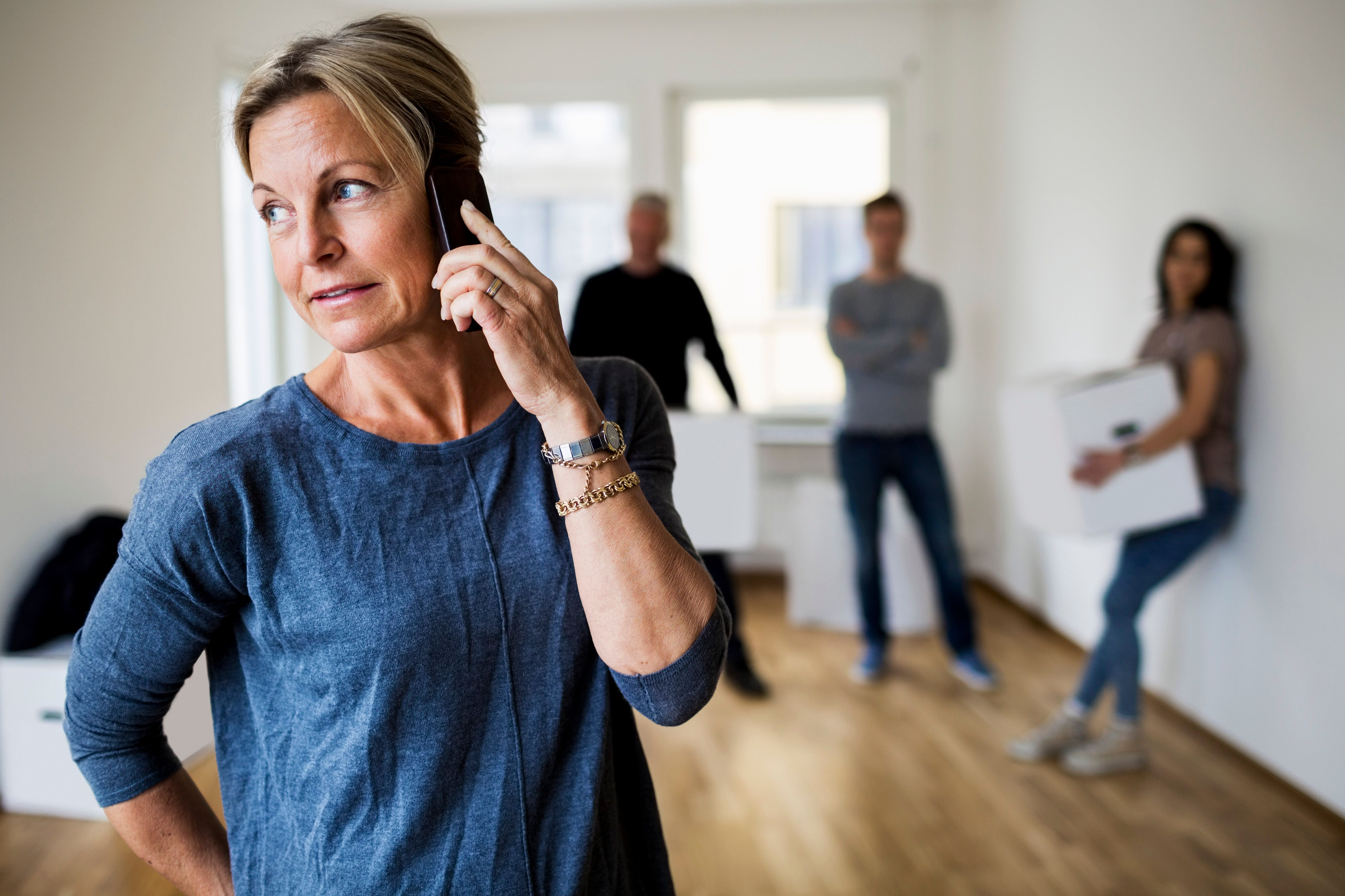 Eine Frau, die telefoniert, während hinter ihr Menschen stehen. | Quelle: Getty Images