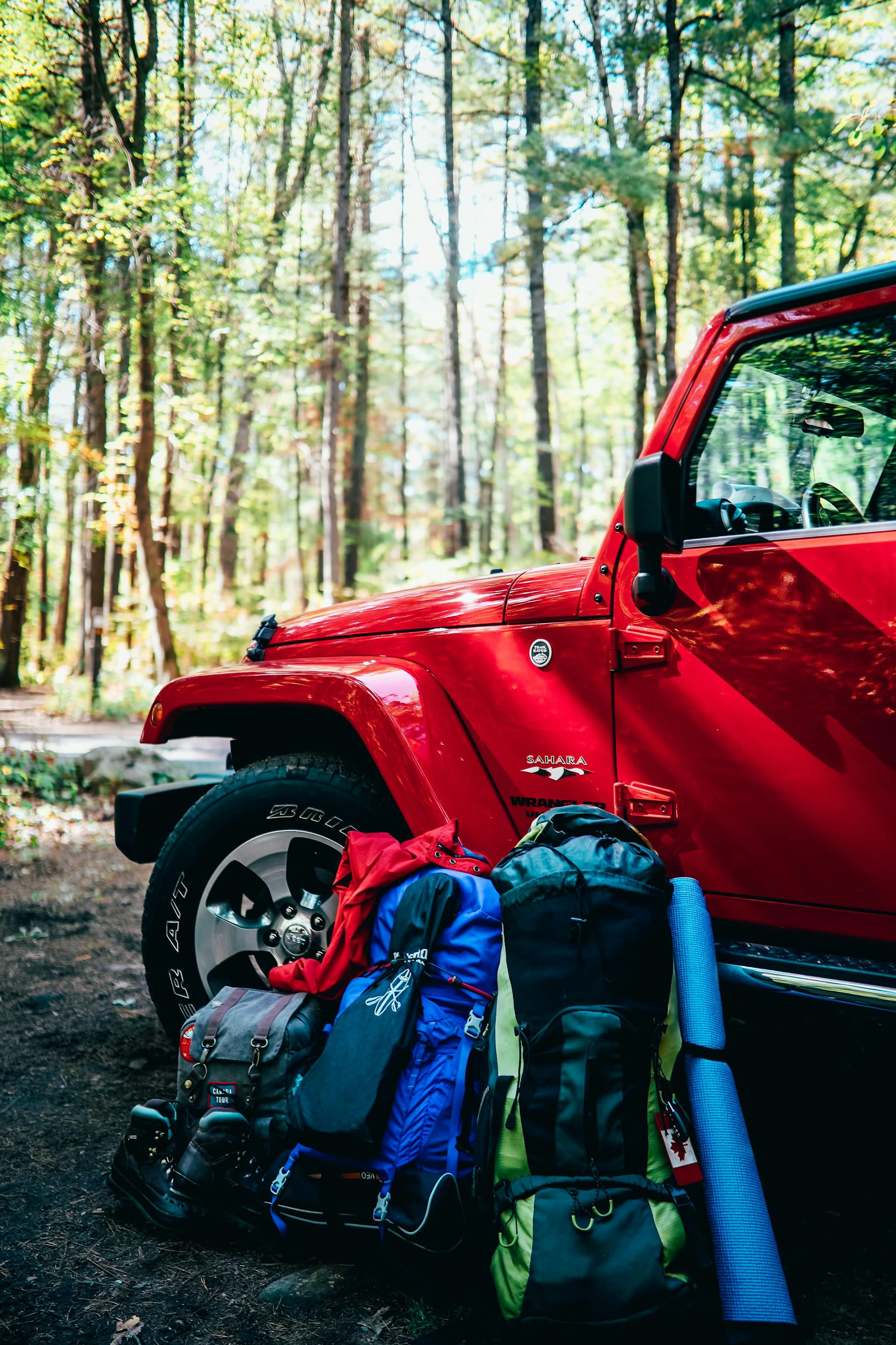 Rucksäcke und Campingausrüstung lehnen an einem Auto | Quelle: Pexels