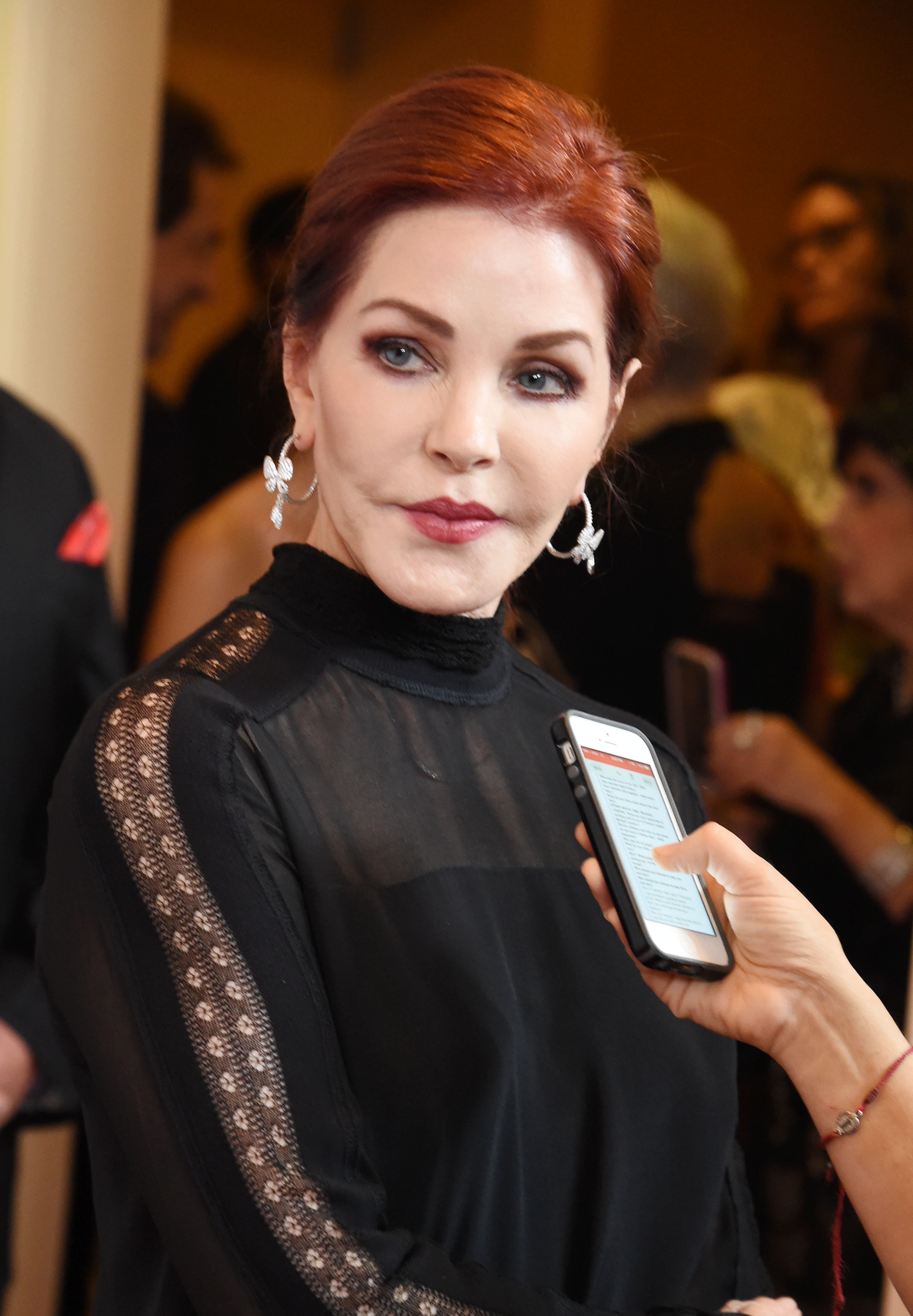 Priscilla Presley nimmt sich Zeit für ein Interview, während sie am 24. Oktober 2015 an der „Last Chance for Animals“-Benefizgala im Beverly Hilton Hotel in Beverly Hills, Kalifornien, am 24. Oktober 2015. Sie trug ein schwarzes, hochgeschlossenes Oberteil mit transparenten Spitzenbesätzen an den Ärmeln und am Ausschnitt, dazu auffällige Diamantohrringe und ihr tiefes Rotbraun, das zu einer ordentlichen Hochsteckfrisur zurückgesteckt war. | Quelle: Getty Images
