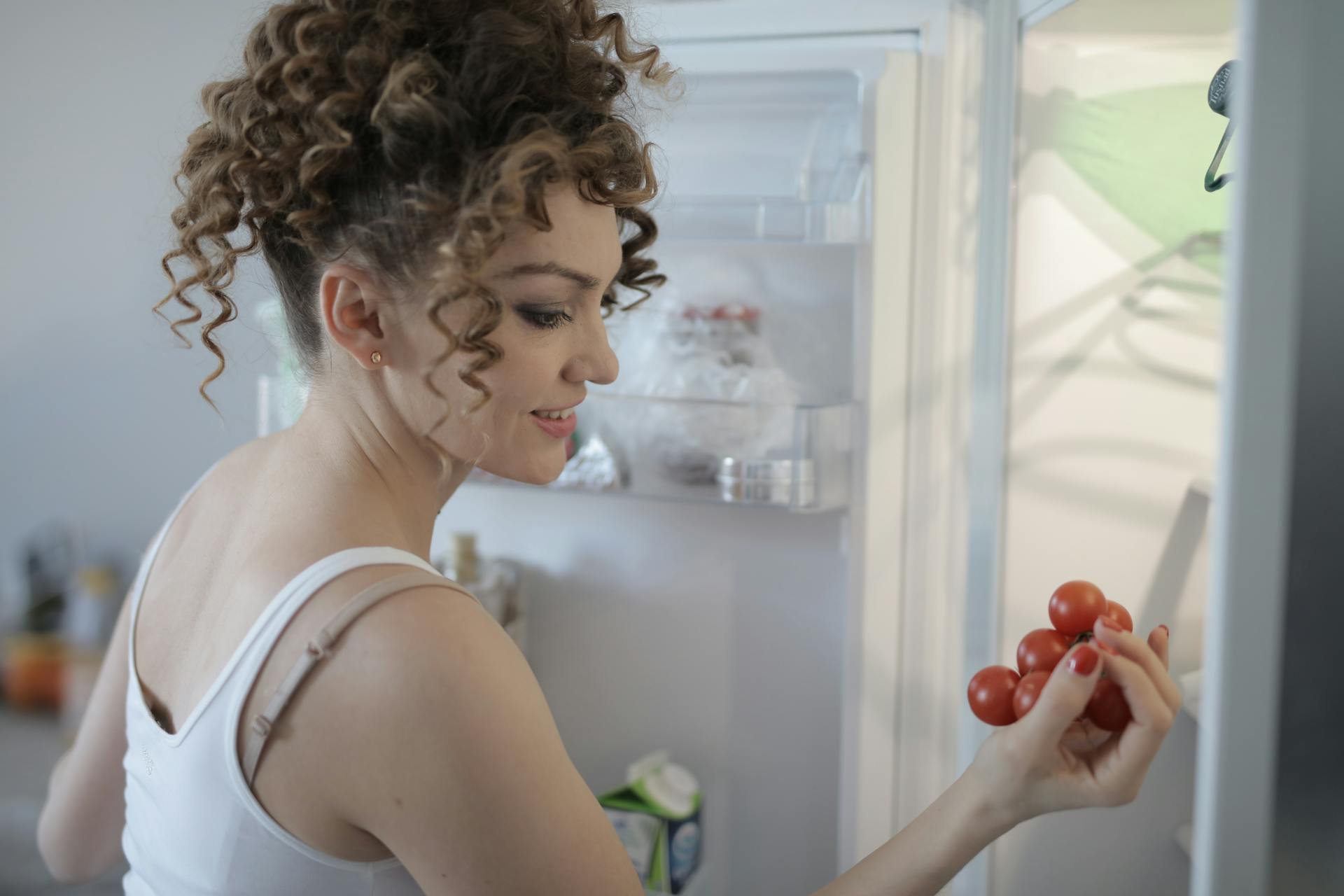 Eine Frau sortiert Lebensmittel in einem Kühlschrank | Quelle: Pexels