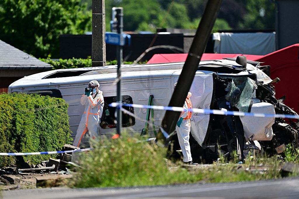 Ein Polizist macht Fotos neben einem beschädigten Bus am Unfallort, nachdem am 26. Mai 2026 am Bahnübergang Vierhuizen in Buggenhout, etwa 20 km nördlich von Brüssel, ein Zug in einen Schulbus gerast war. | Quelle: Getty Images