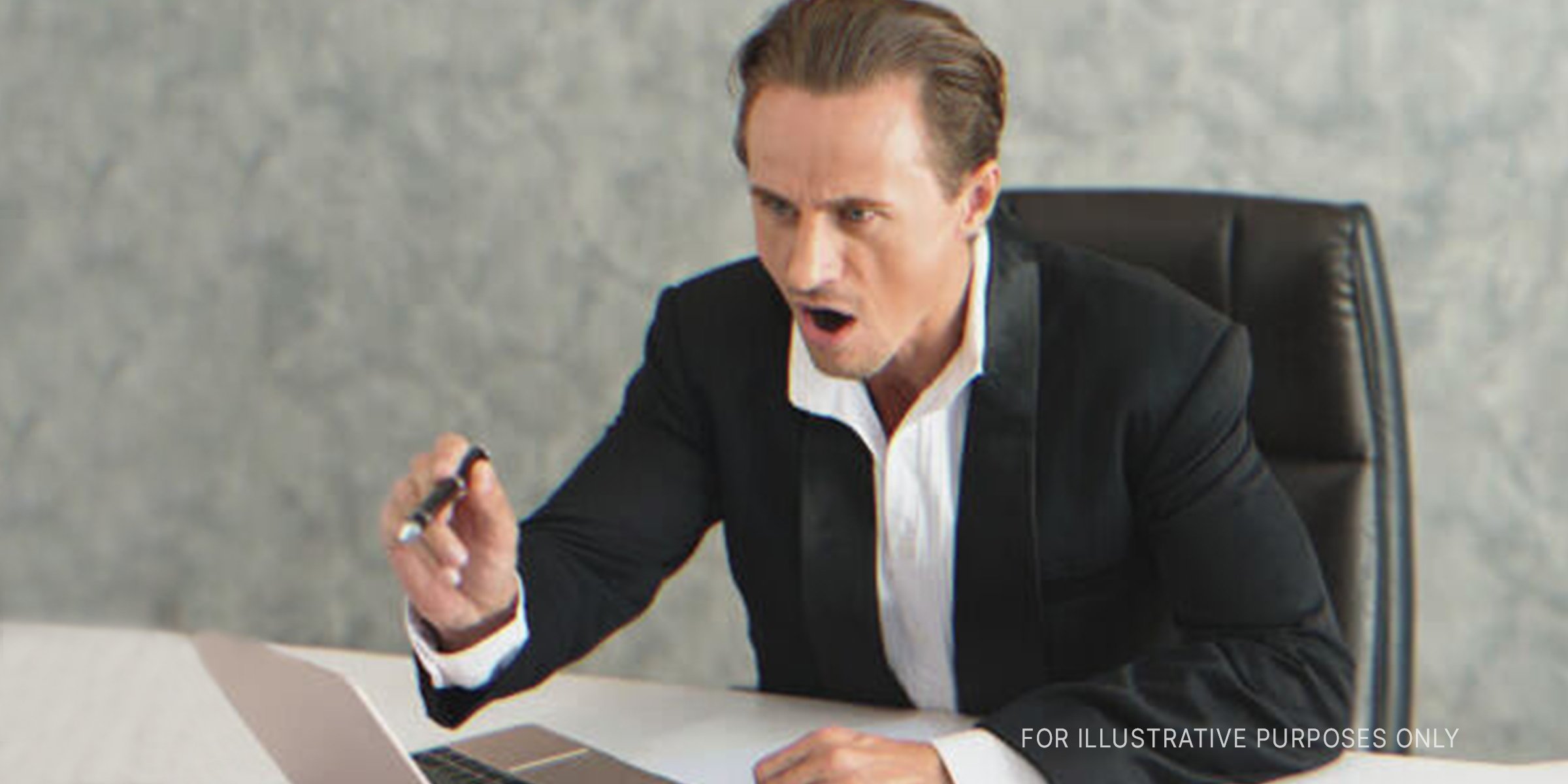 Ein Mann sitzt an einem Schreibtisch und zeigt wütend auf jemanden. | Quelle: Shutterstock