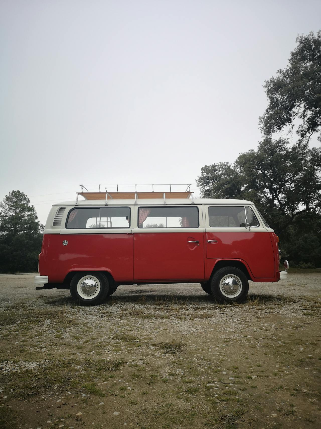 Ein roter Oldtimer-Minivan, der auf einer kargen Wiese geparkt ist | Quelle: Pexels
