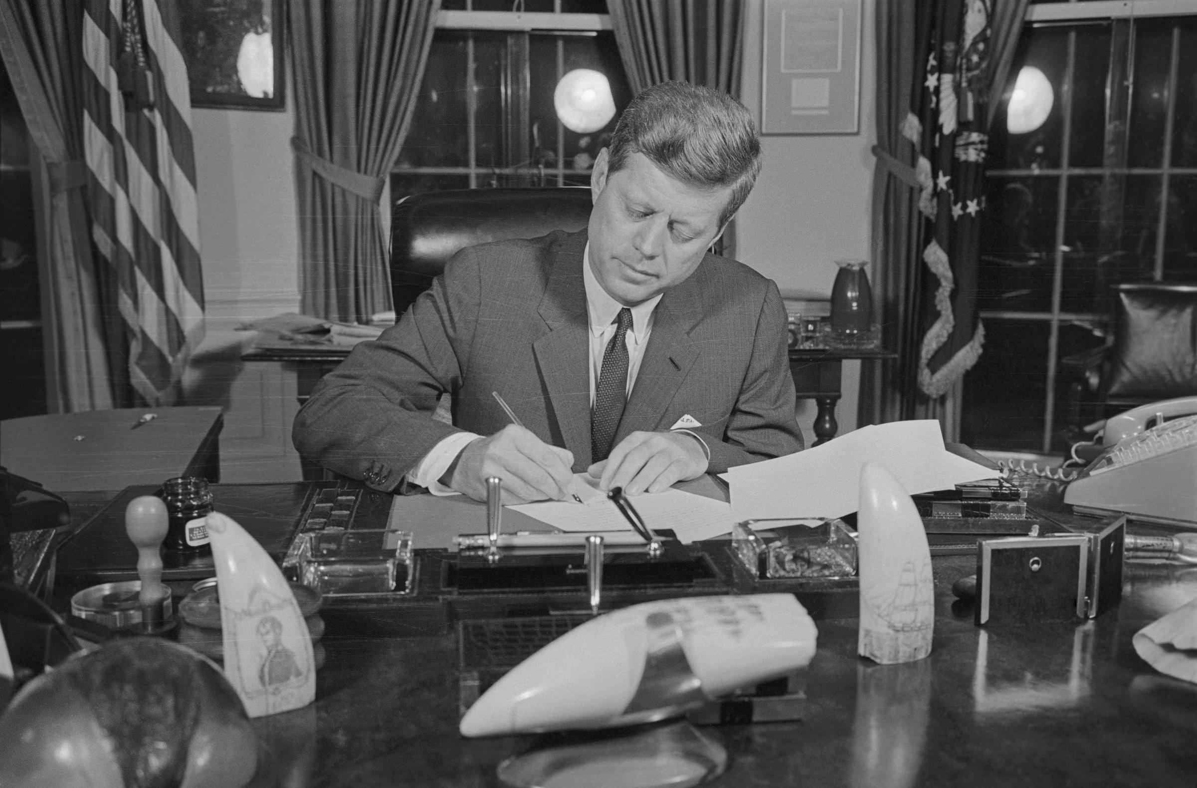 Der ehemalige Präsident John F. Kennedy bei der Unterzeichnung der Blockadeverordnung in seinem Büro im Jahr 1962. | Quelle: Getty Images