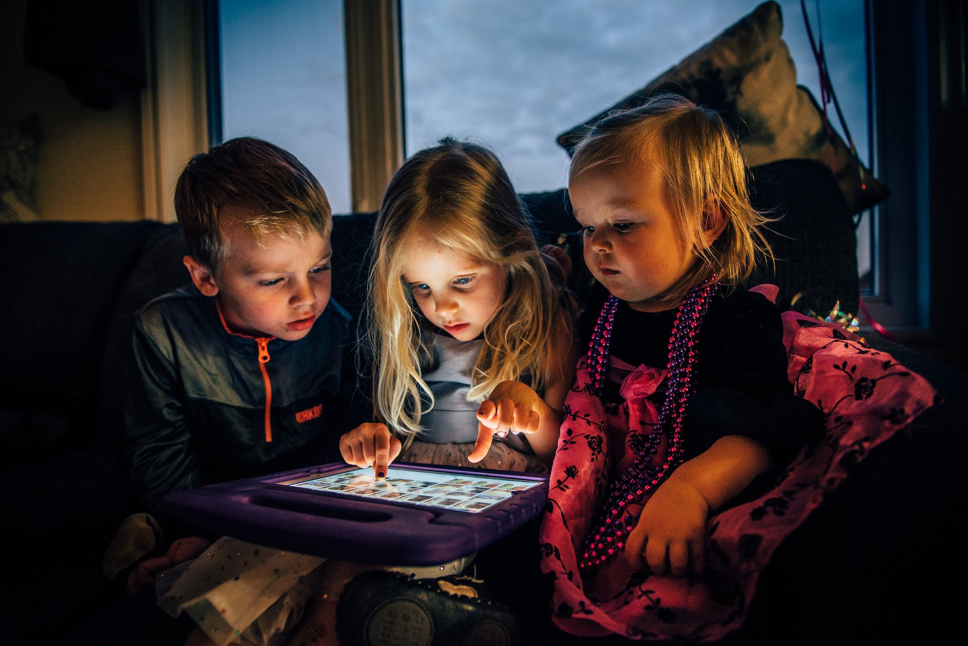 Drei Kinder schauen auf ein Tablet | Quelle: Pexels