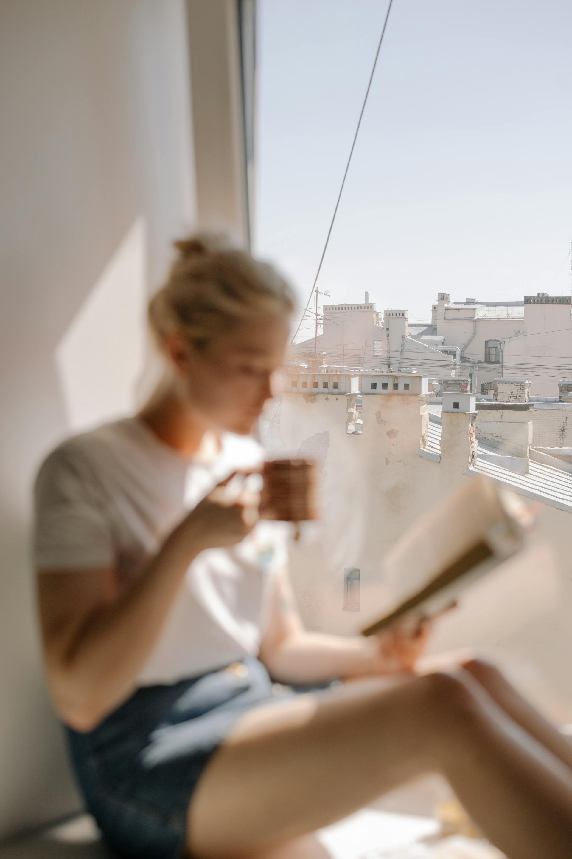 Eine Frau trinkt Kaffee in der Nähe eines Wohnungsfensters | Quelle: Pexels